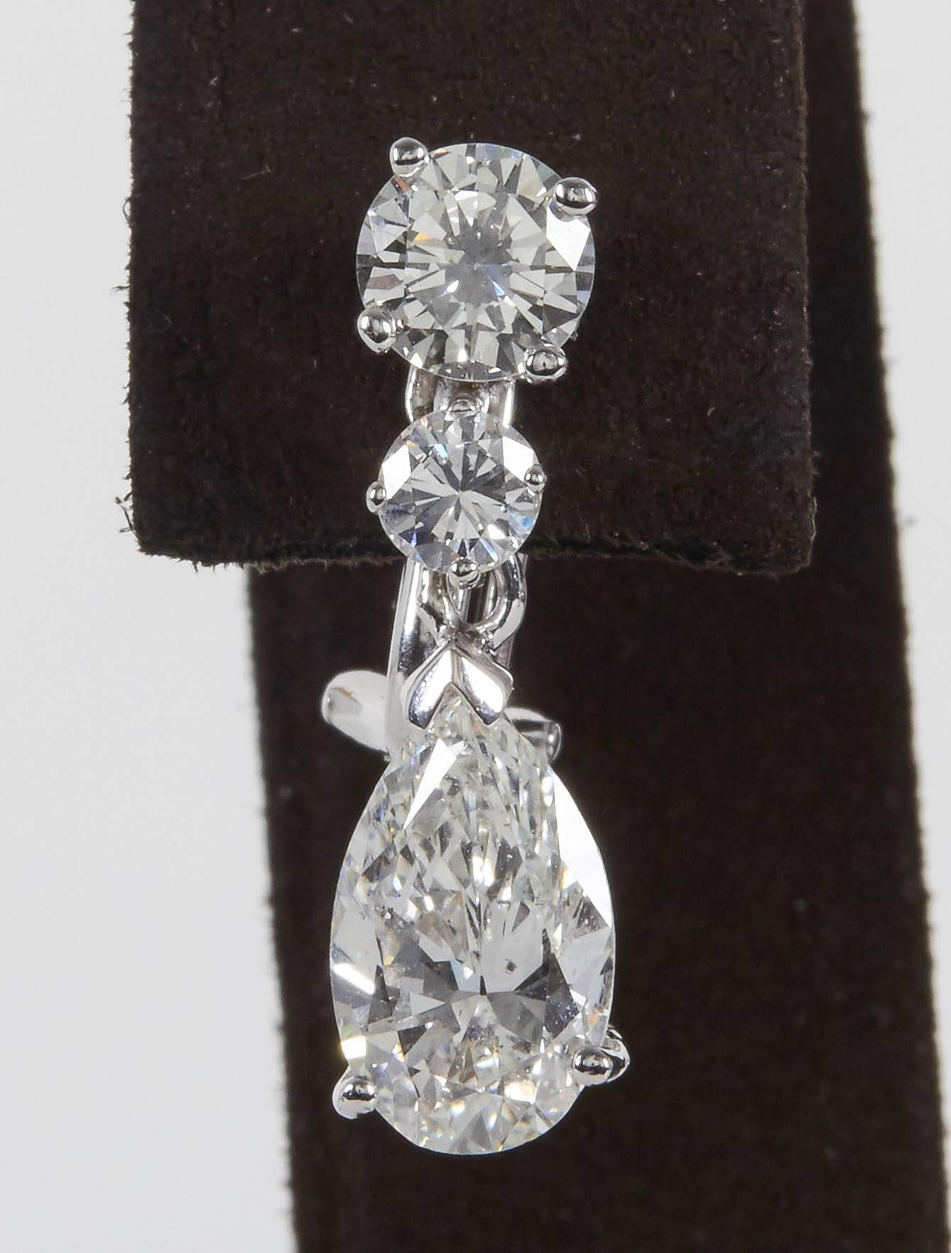 
A beautiful pair of classic diamond dangle drop earrings set in a timeless design. 

3.00 cts (total) of pear shapes suspended from 1.30 carats (total) of round brilliant cut diamonds. 

The diamonds are near colorless white, H/I VS1-SI1. 

The