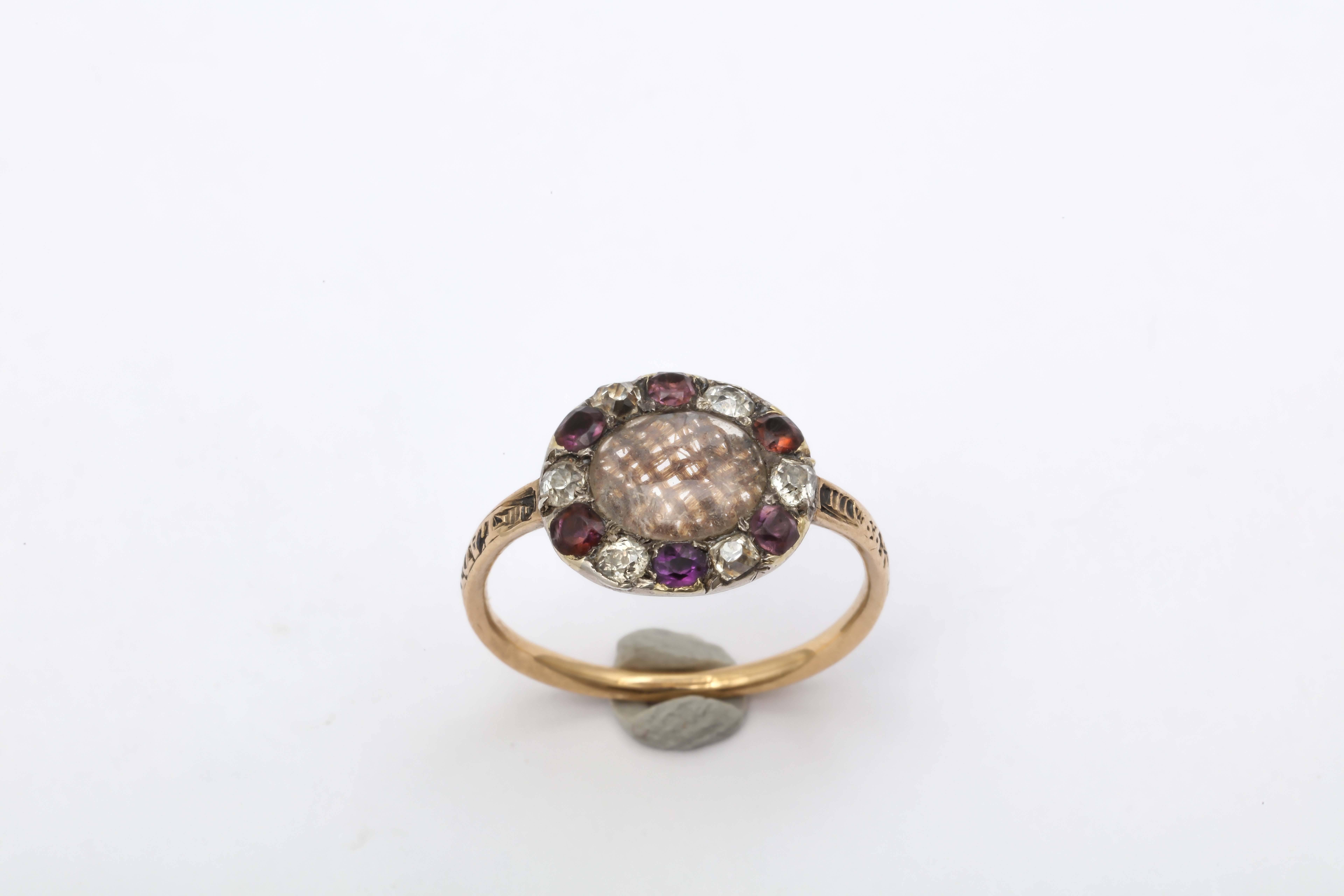 Stunning Georgian ring with a central crystal locket of woven hair surrounded by amethysts and diamonds. Amethysts have long been used as the symbol of royalty-purple being their color- and a symbol of piety for the church. The shank has worn