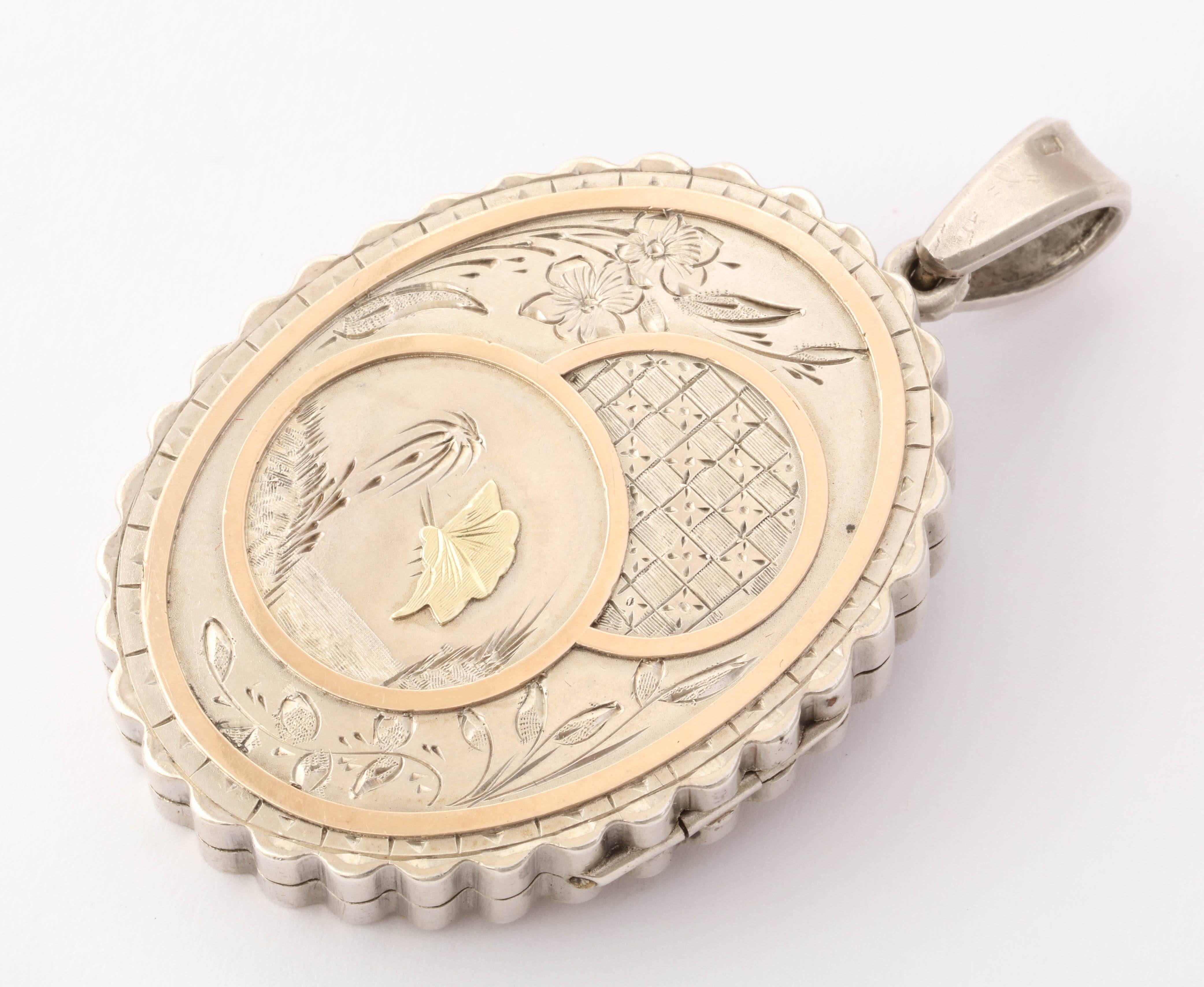 Resembling a small painting in silver, a butterfly at a Suessian flower, a body of water , geometry, flora and asymmetry, all hallmarks of the Aesthetic Movement, are engraved on this locket face. The outer oval frame,  butterfly and the borders of