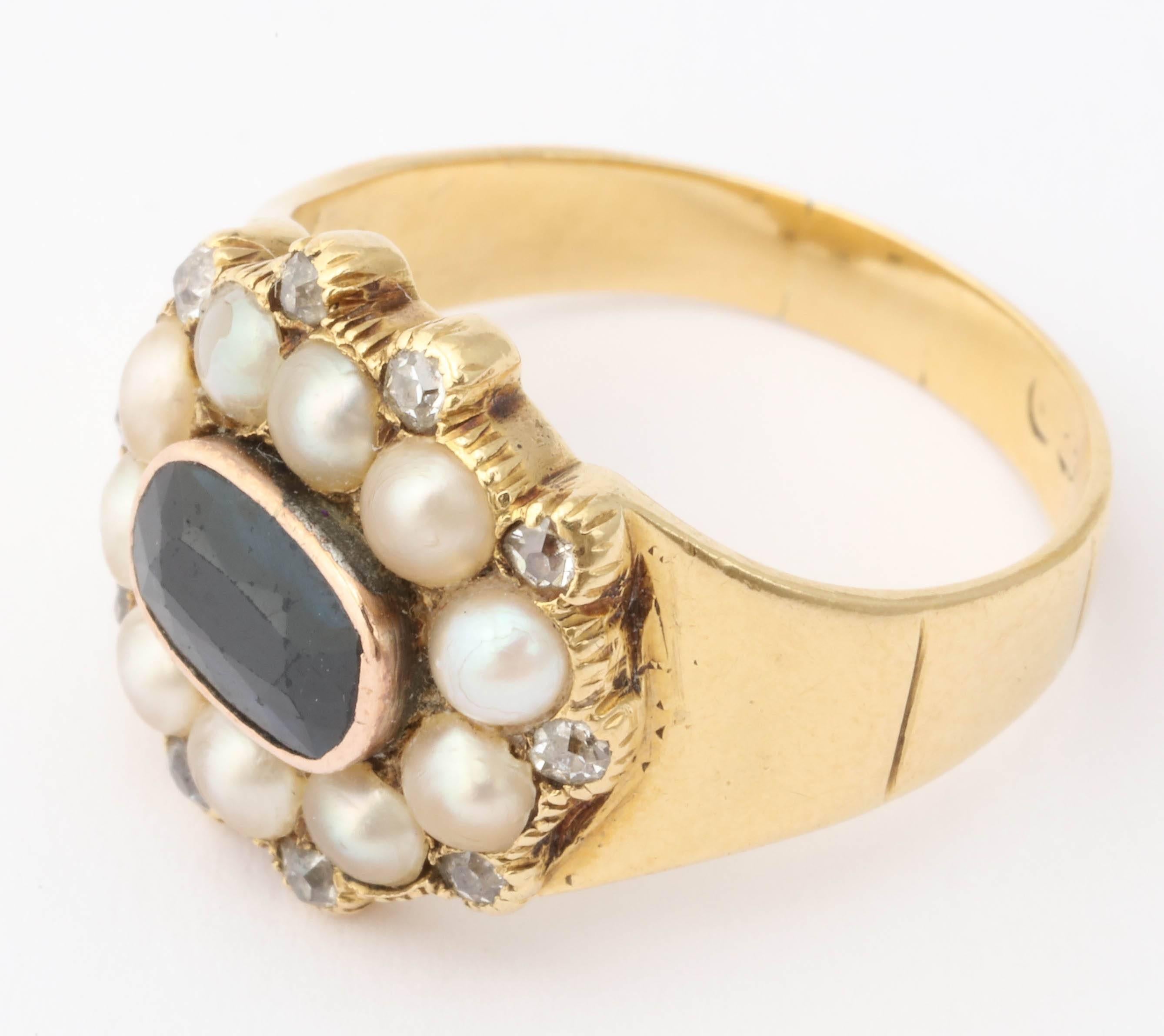 Far more lovely in person is the arresting early Victorian ring, from the young years of Queen Victoria. set with rich blue natural sapphire, creamy white natural pearls and bordered by diamonds in glowing combination. The darker pearls of the photo