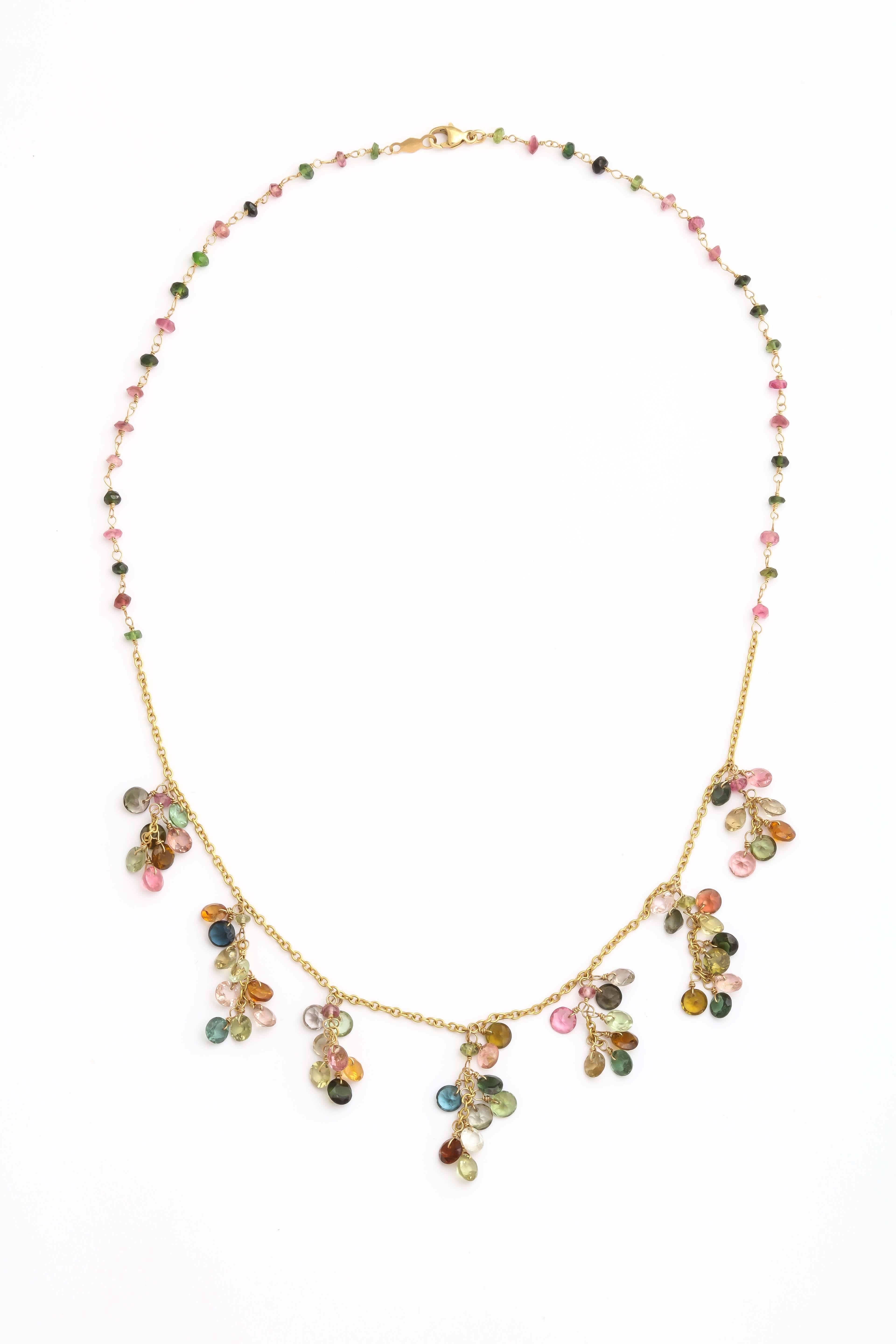 Each group of round faceted multicolored tourmalines is delicately wrapped with a gold wire and attached to form a sparkly bundle. The bunches are then attached to a gold chain and finished with a tourmaline bead wrapped chain. The necklace is 15