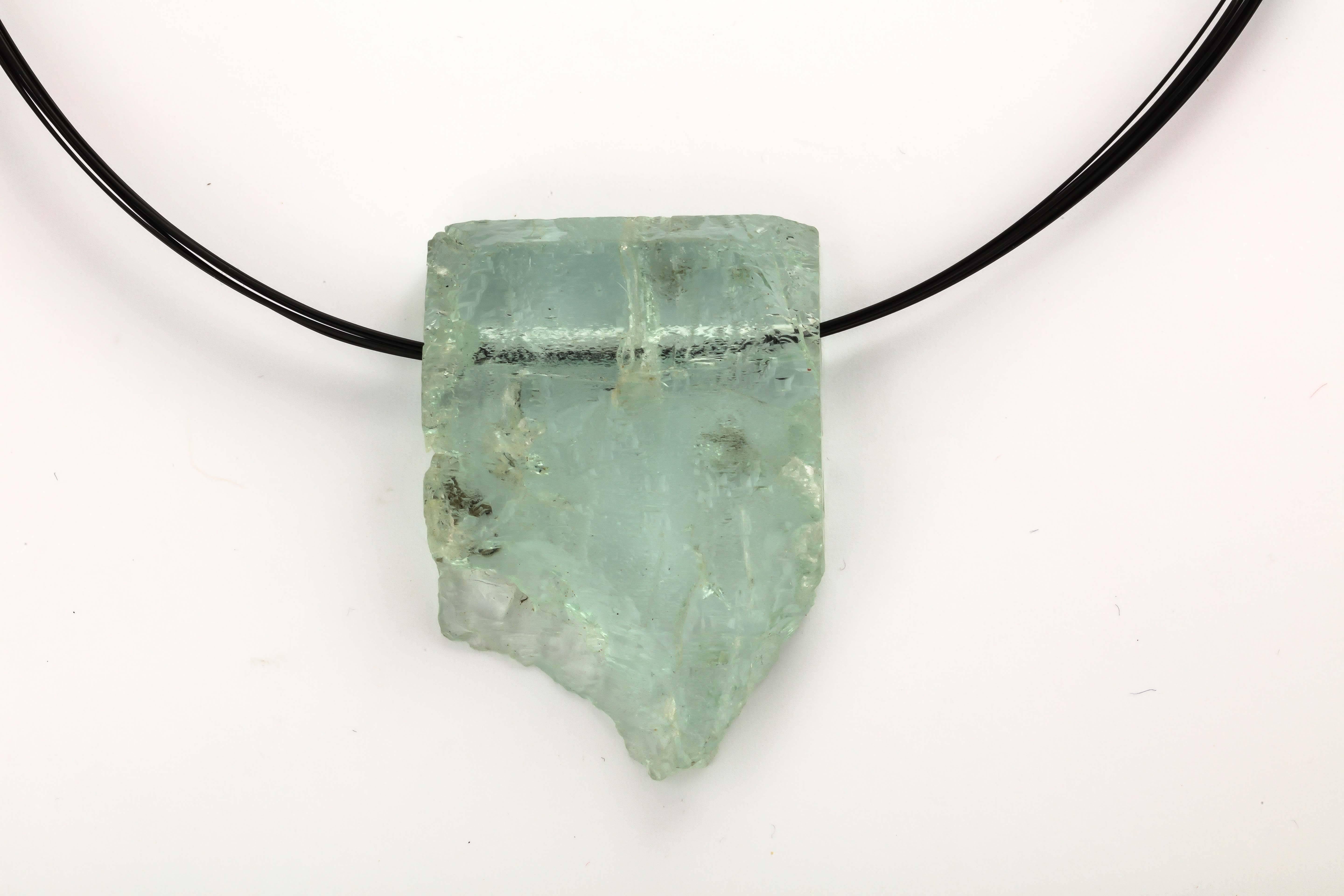 This raw aquamarine slice is one of kind and straight from nature. One side is polished smooth, the other is natural. The aqua measures 1 1/2 in across and 2 in. from top to the bottom point. The  necklace is a 12 strand nylon cable finished with an