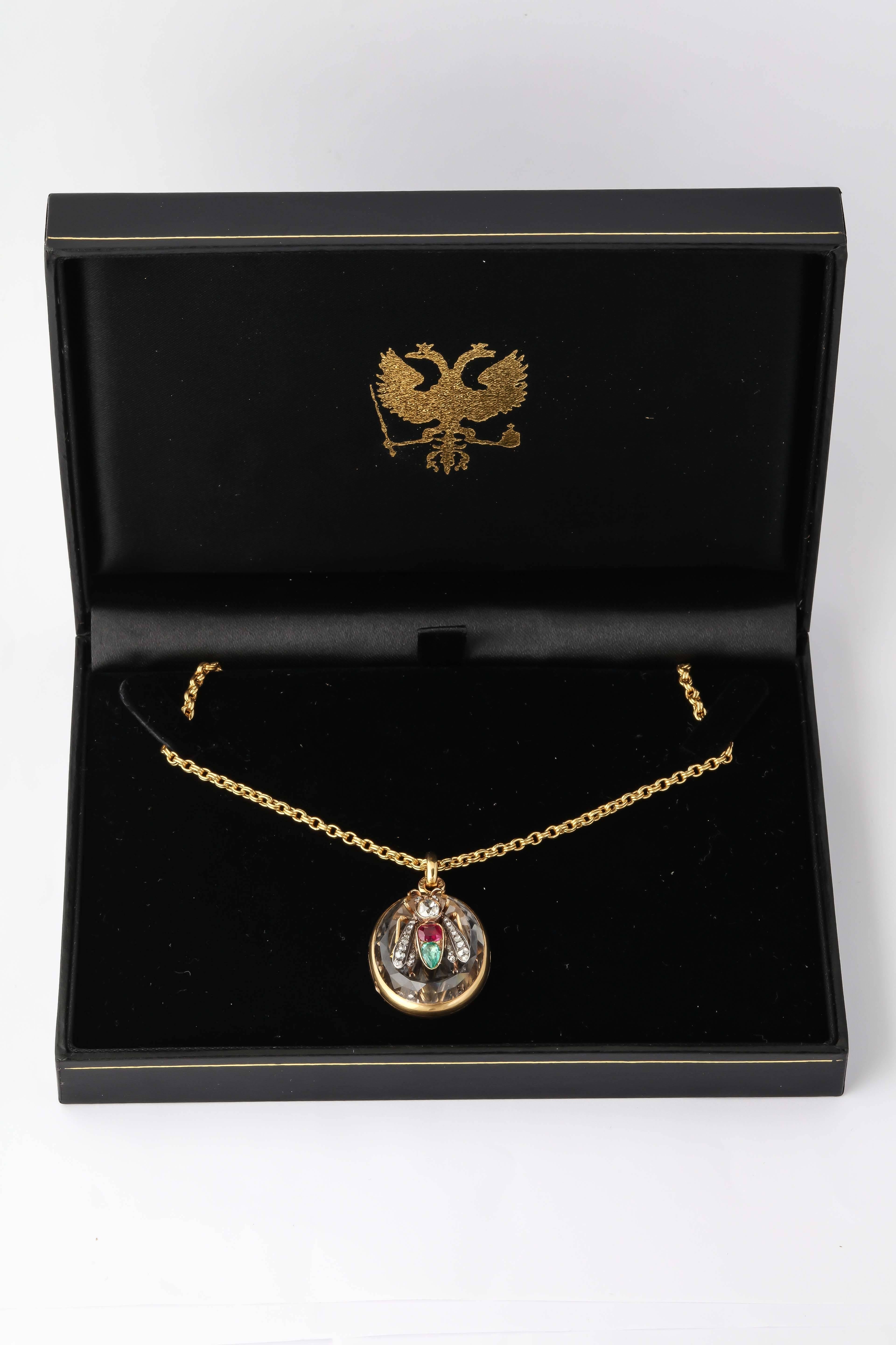 A beautiful gemset 18k gold rock crystal locket, the cover applied with an articulated gold fly, its body and head set with a cushion-cut ruby, a pear-shaped emerald and an old European- cut diamond, its wings and eyes set with rose diamonds.