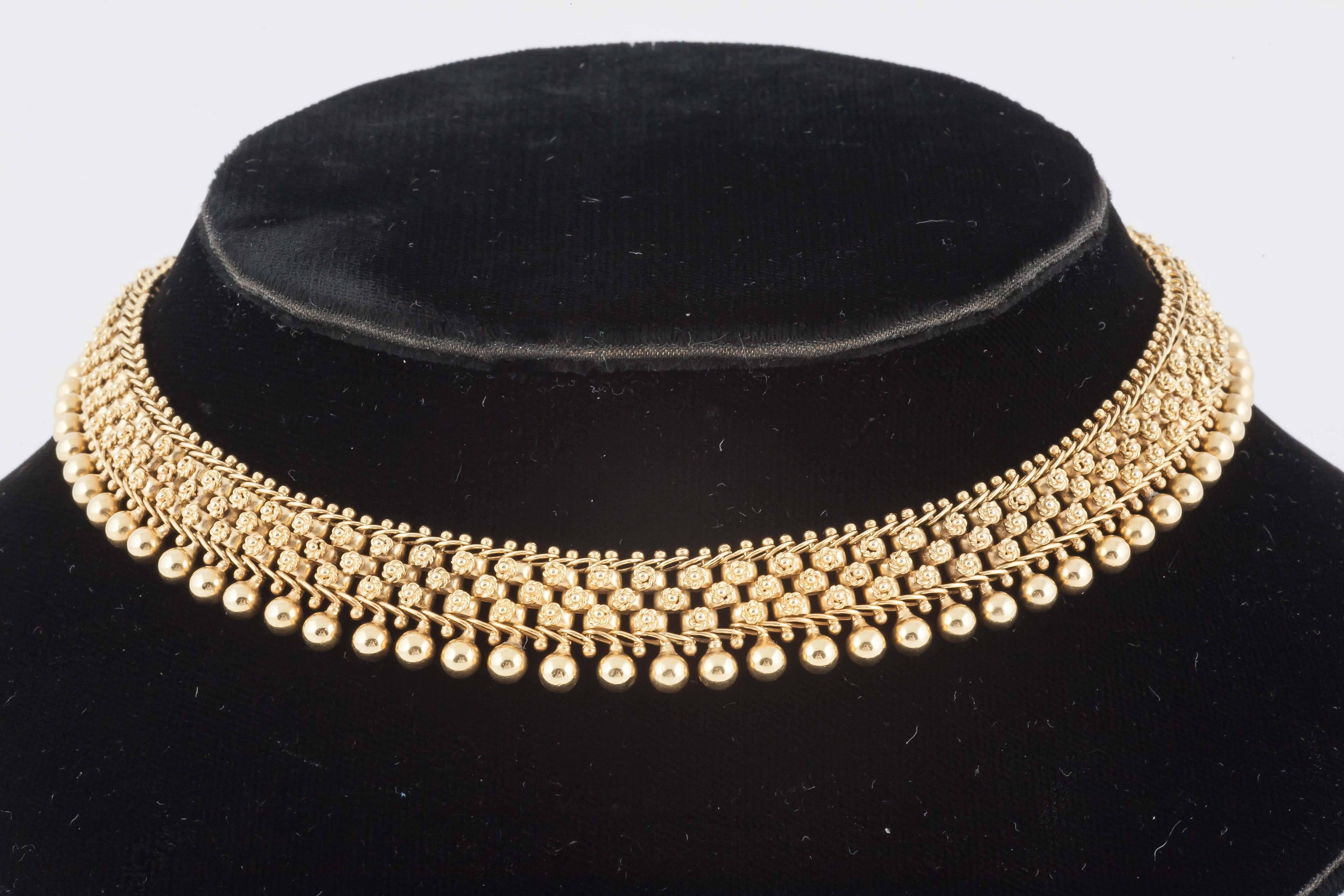 A fine quality, 15 carat yellow gold collar necklace of wire work motifs and beaded border, excellent colour and condition, to be worn at base of neck. English c, 1870