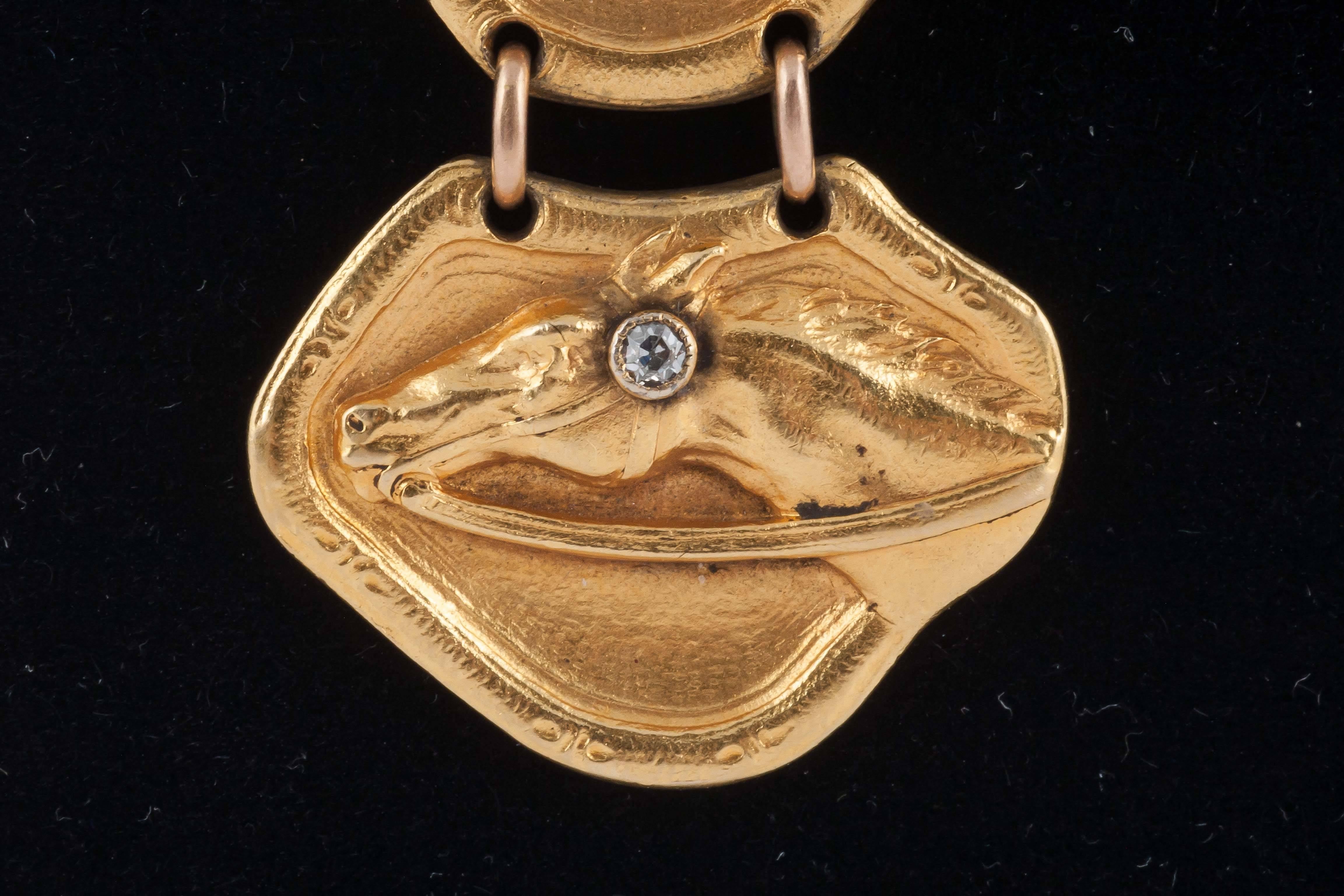 A finely made gold fob pendant of four, racehorse heads, each with a single diamond to the bridle, the patina and colour  original. Probably American c, 1900