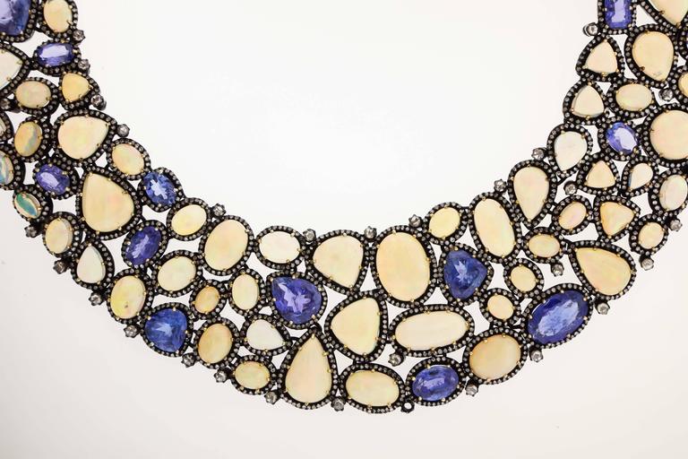 A magnificent necklace by JS Noor combines Ethiopian cabochon opals (110.50 cts), blue tanzanites (70.7 cts) and 19.23 carats diamonds are set in oxidized sterling in a fabric-like bib necklace, 18