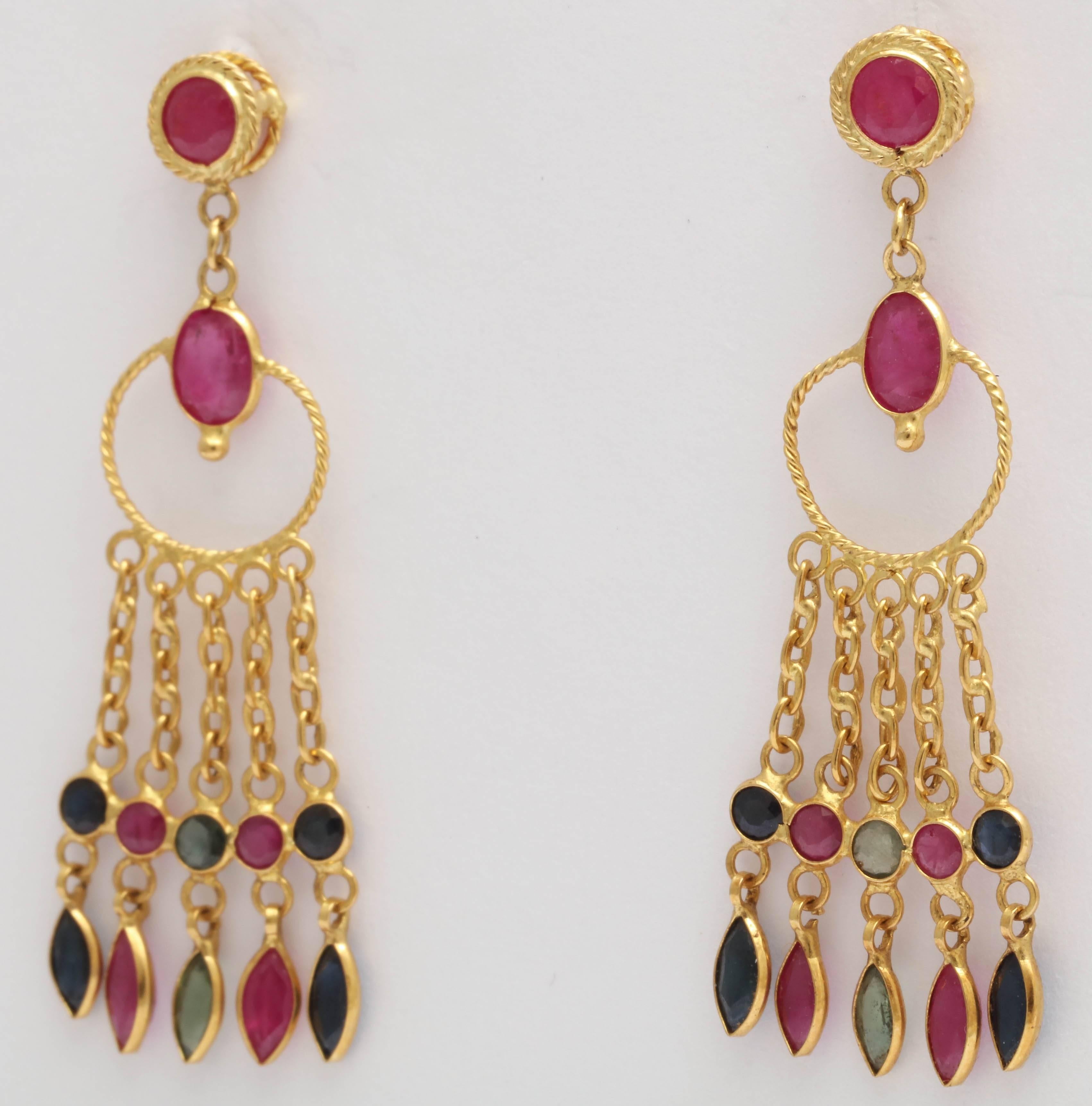 These earrings are made with red rubies, and green and blue sapphires set delicate 18 kt gold bezels. The top is a round ruby with a twisted wire bezel setting, post and back. These earrings dangle beautifully, are light, and colorful.