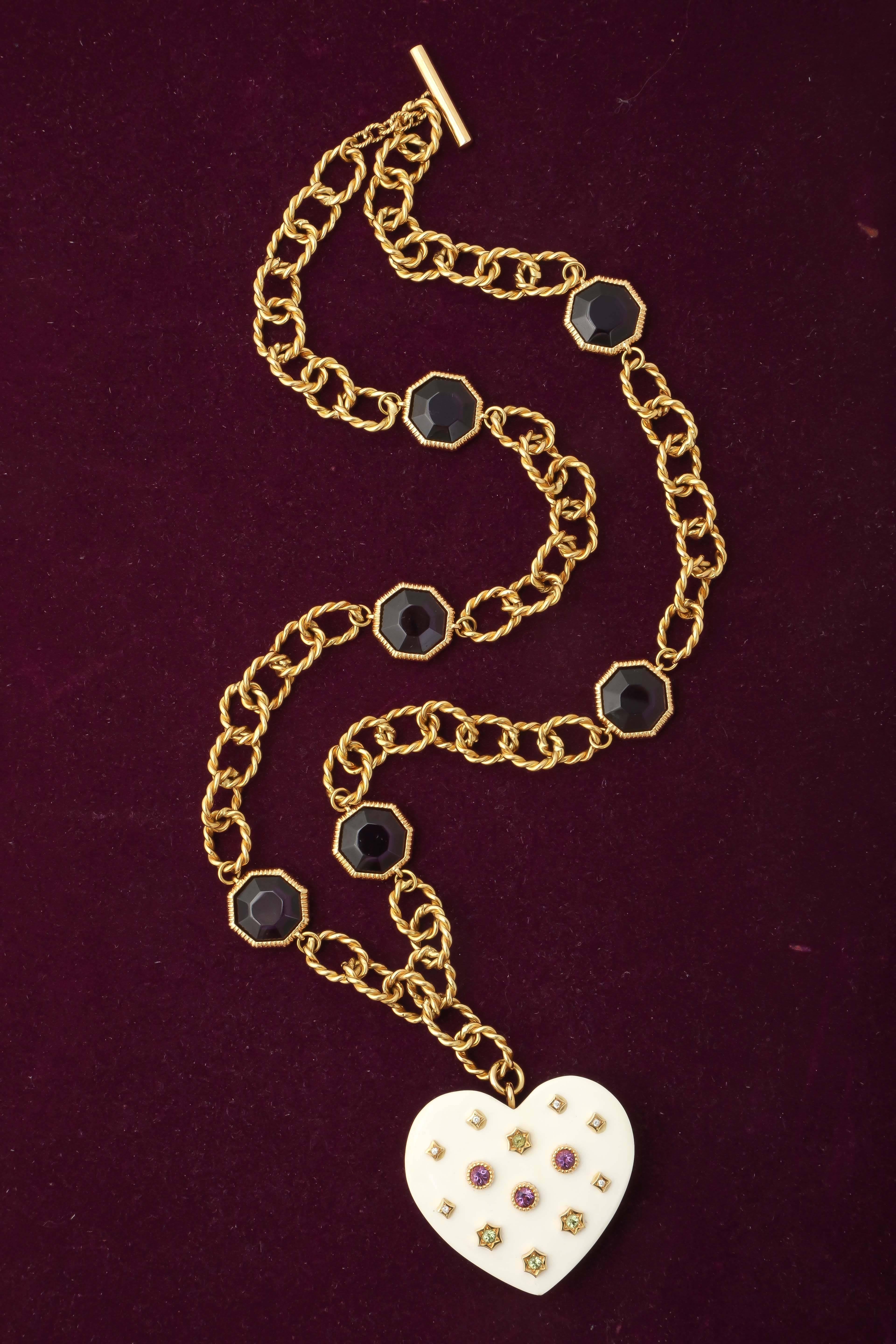 18kt yellow gold link Chain/Necklace Designed With A Large Heart Hanging From The Bottom Measuring 1.25 inches in length and 1.75 inches wide. Heart Made Of White Ceramic And Embellished With Faceted Amethyst,Peridot & Diamond Stones. Chain Also