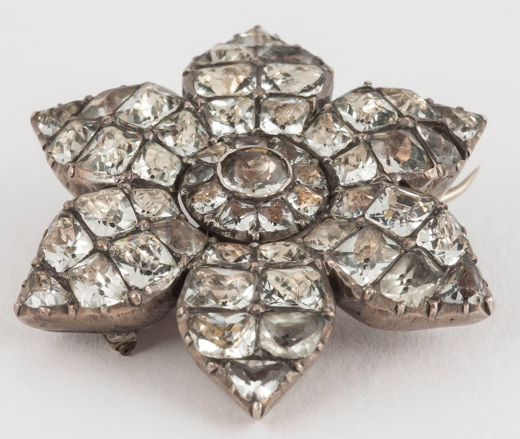 A rare antique brooch in the design of a flower dating from the reign of George III. The design has six petals, it is set with shaped and foiled white pastes and mounted in silver. The paste is in excellent condition. The brooch fitting is a later