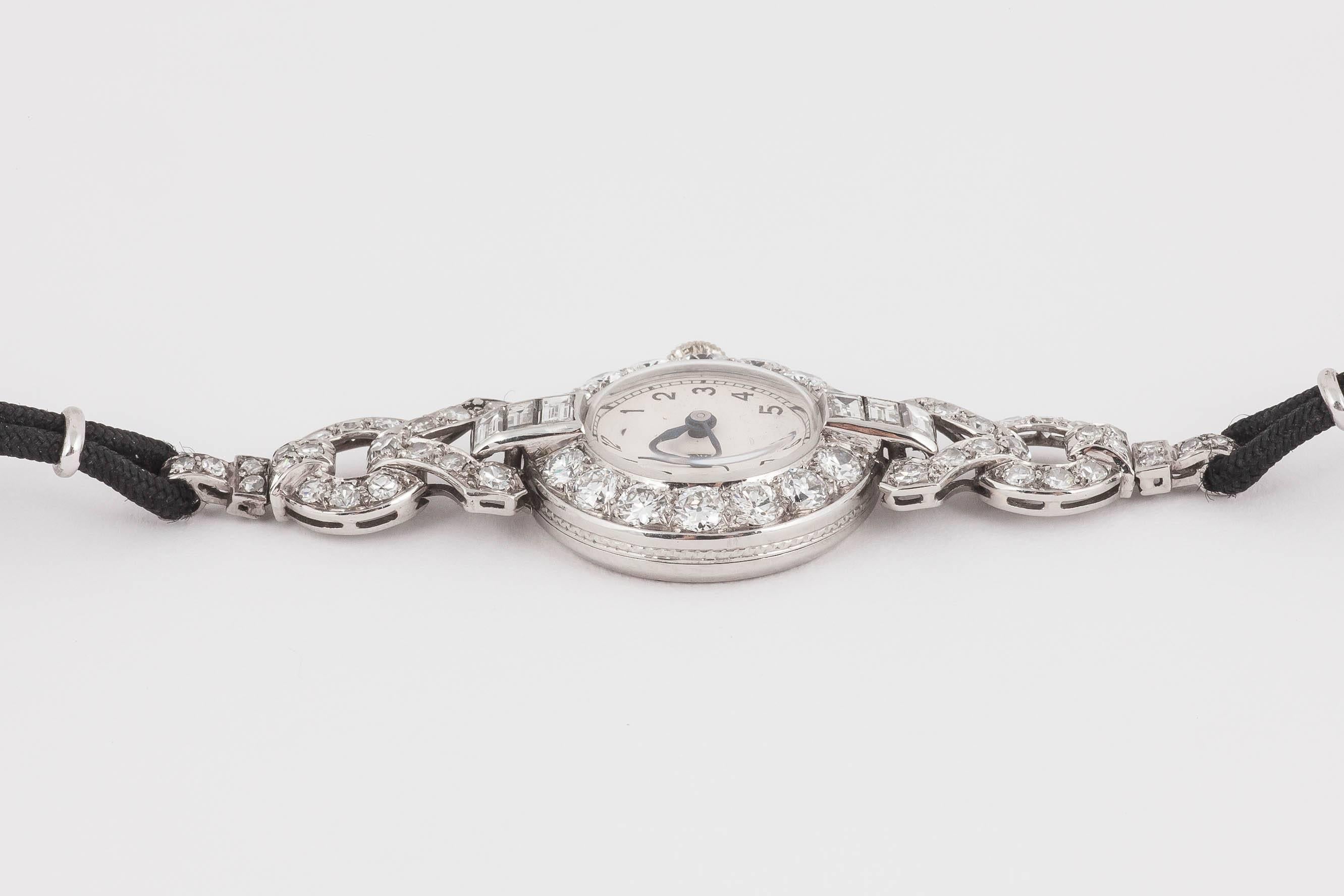 A 1920s ladies evening watch signed Tissot, set with old cut brilliant diamonds and baguette cut shoulders, mounted in platinum. 17 jewelled lever movement [54 diamonds], good colour and clarity, approximately 2.5 carats.  Numbered 7018 on reverse. 