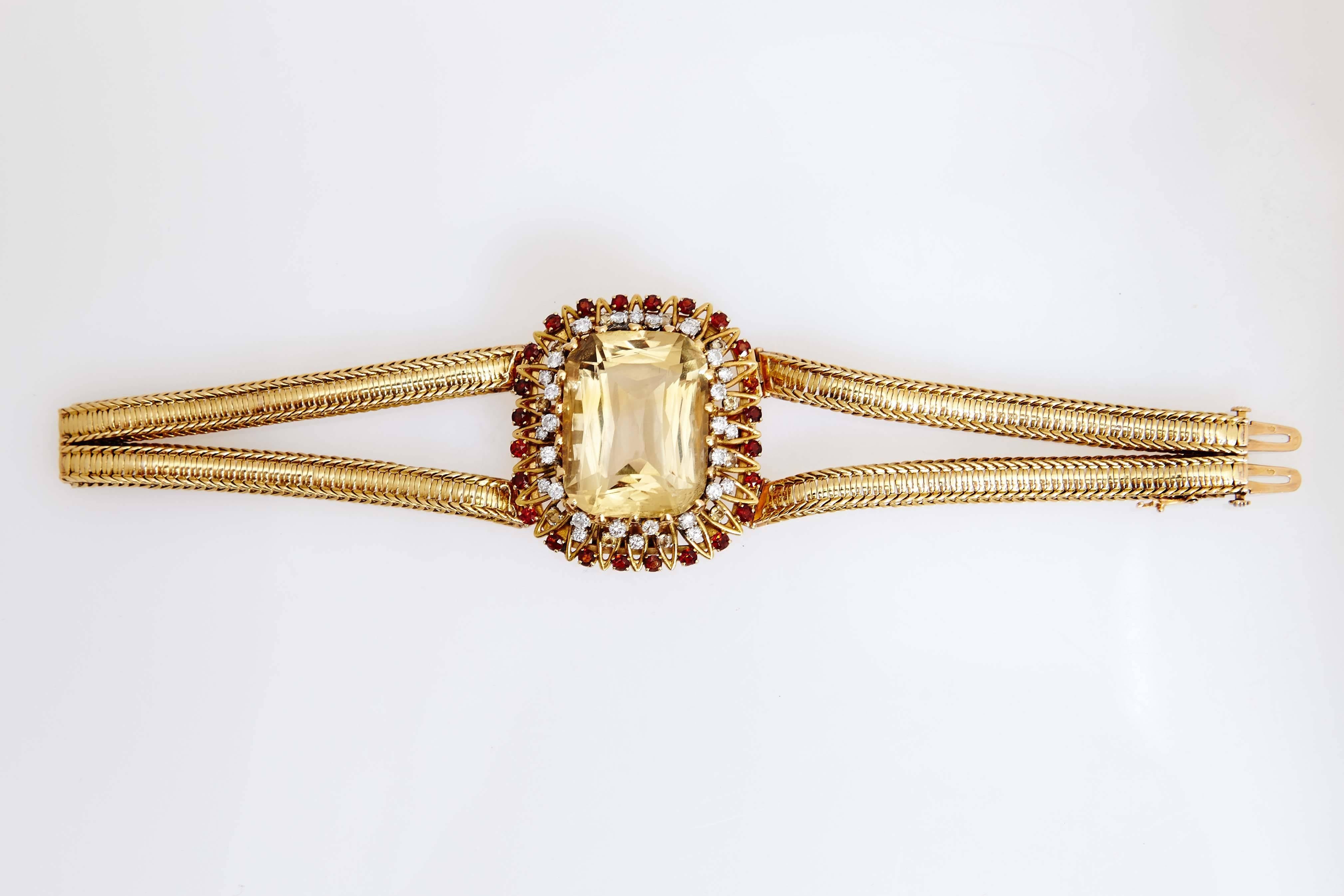 An exquisite retro gold bracelet by Pierre Sterle, showcasing a large citrine, highlighted with diamonds and garnets. Made in Paris, circa 1950. 