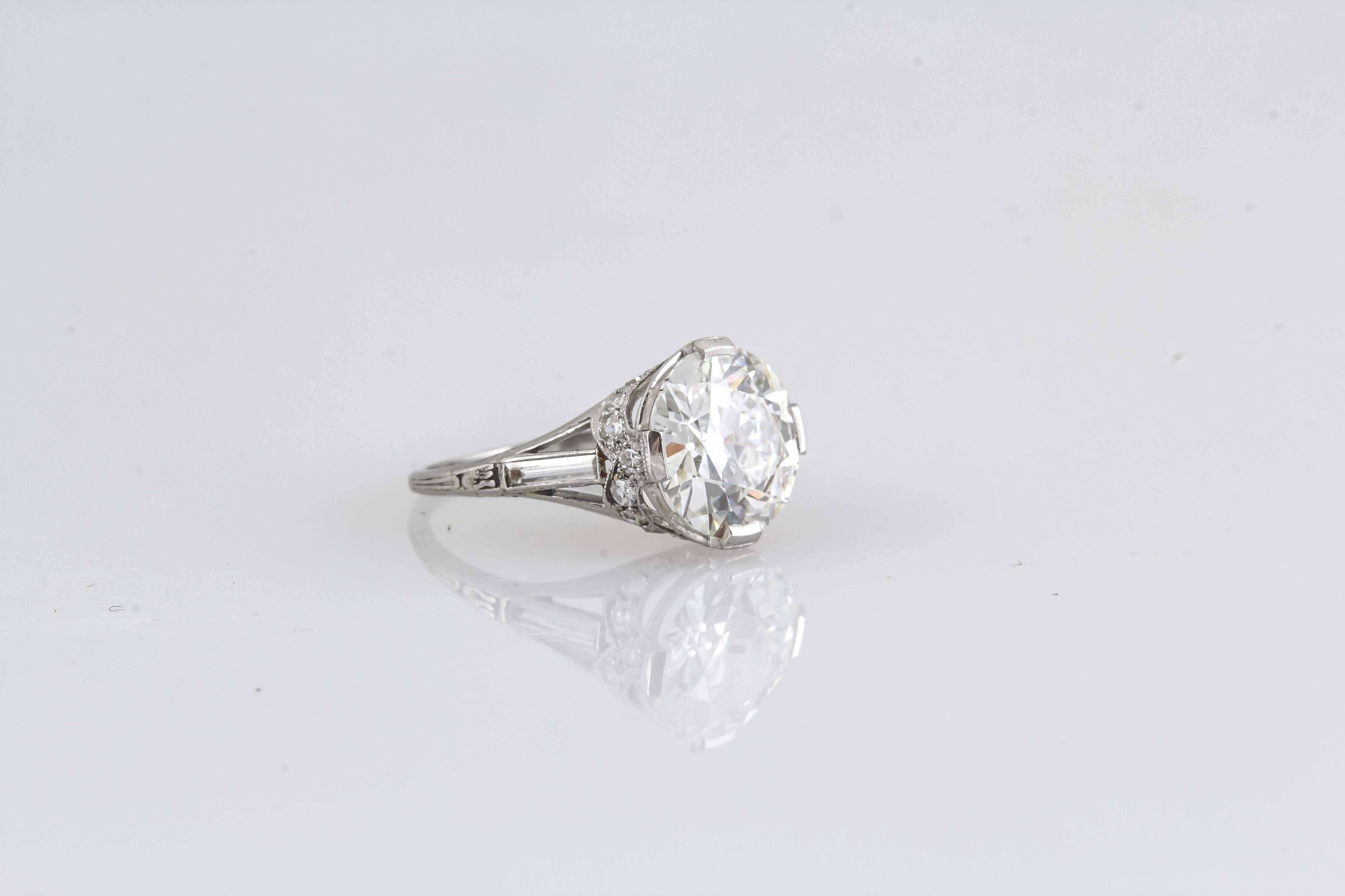 Finement réalisée en platine, elle est ornée d'un diamant central de taille ancienne européenne certifié par la GIA et pesant 4,06 carats. Couleur G.  Clarté VS2. La bague est ornée de deux diamants baguette sur le côté. Inspiré de l'Art déco