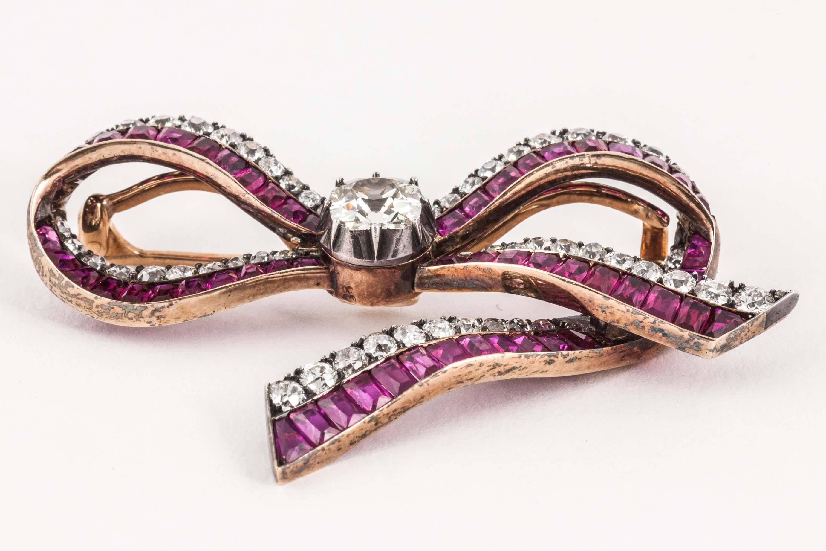 A very fine silver and gold mounted brooch in the form of a ribbon [detachable pin] set with brilliant cut diamonds and shaped burma rubies ,all graduated.The central old mine cut stone weighing approx 2 carats.Marked on pin and body with Austrian