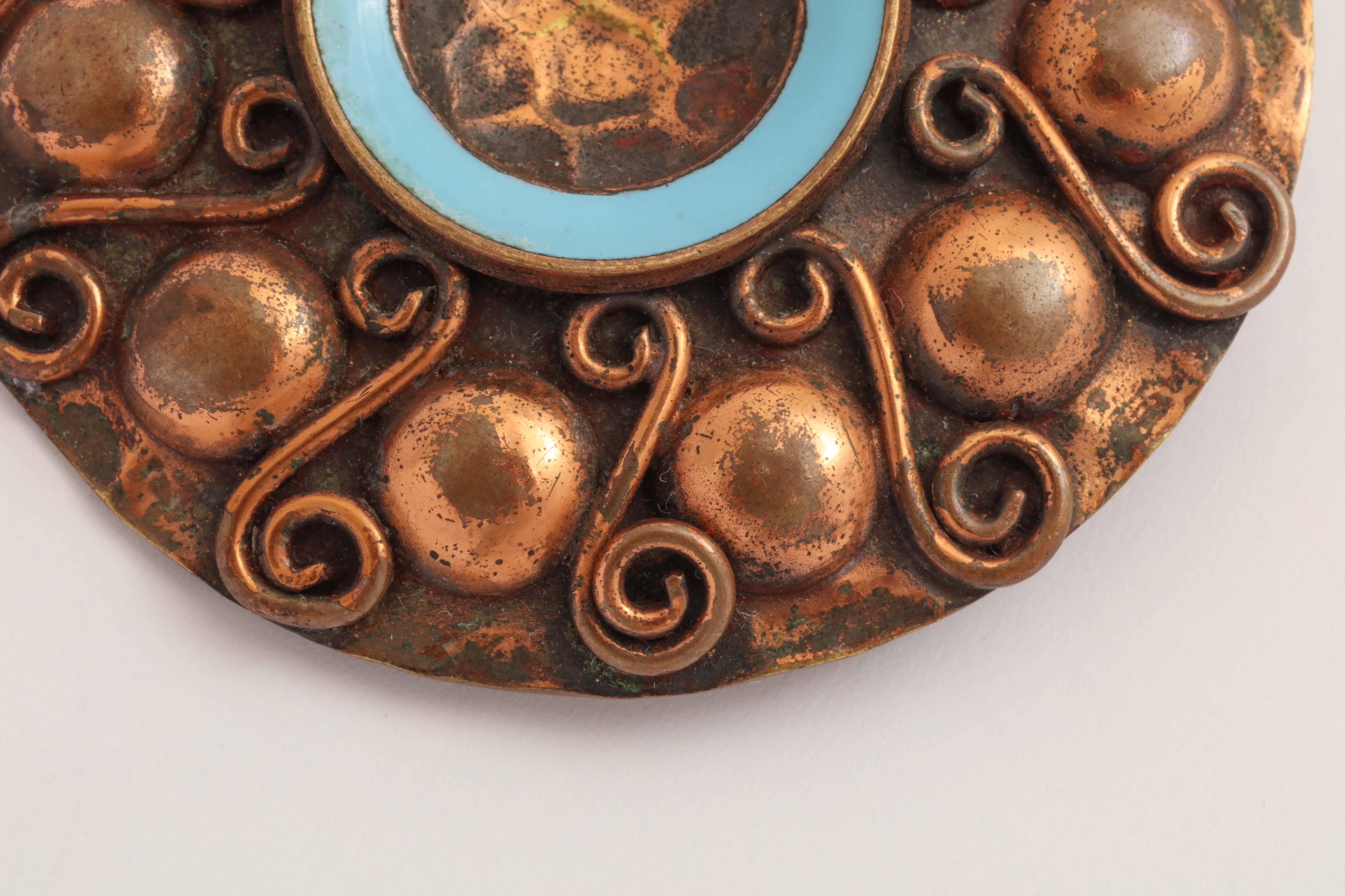Bronze circular with central blue enamel ring and border of alternating demi-spheres and S's.
Jean Augis was President of the Fine Arts Society, Lyon.

Inscribed Jean Augis/ impressed Bronze Emaille Grand Feu on back.