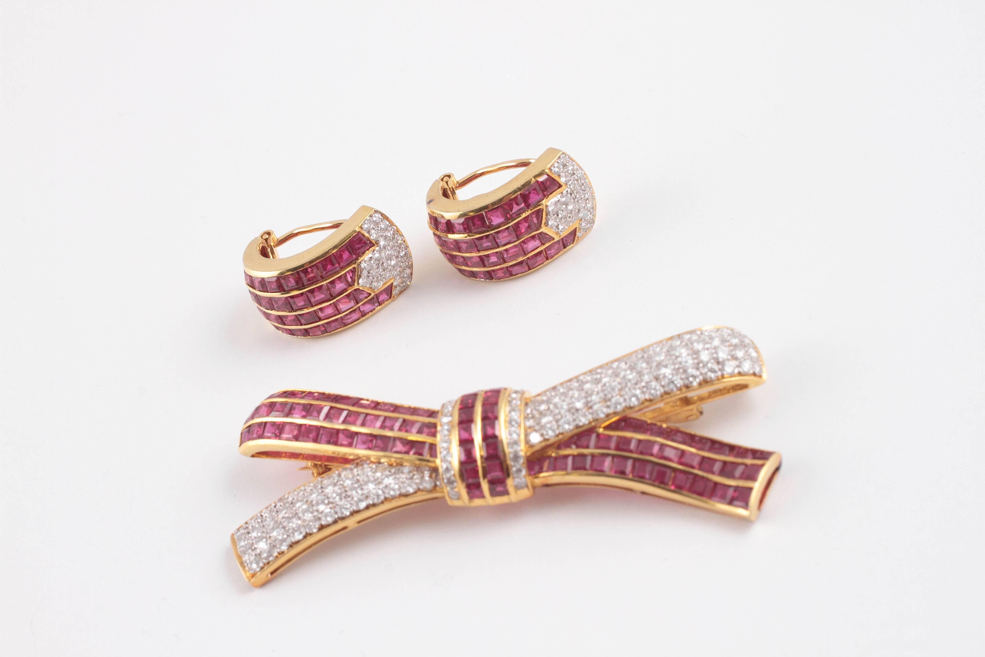 Stunning set for the right outfit!  Invisible and channel-set, rubies along with bead-set diamonds in 18 karat yellow gold.  The brooch is secured with a straight pin clasp and measures 70.00 mm in length.  The earrings are approximately 25.00 mm in