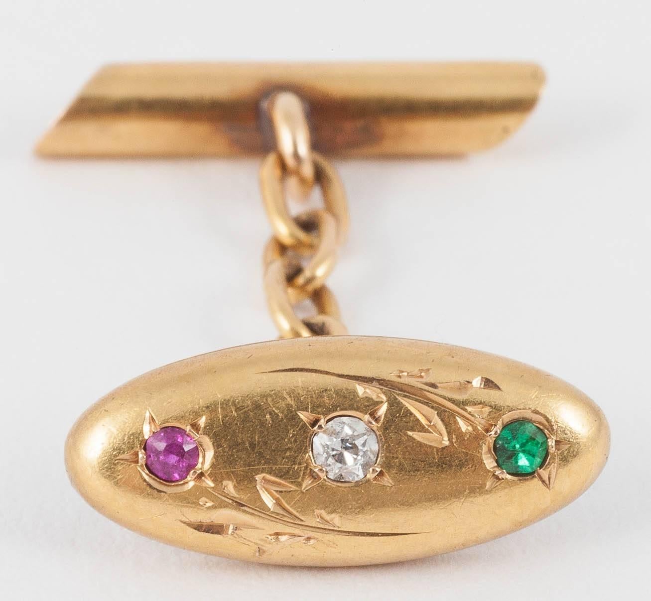 An attractive pair of french,18kt yellow gold cufflinks with engraved floral design,and set with an emerald,old cut brilliant diamond,and a burma ruby.Original baton connections.c,1910