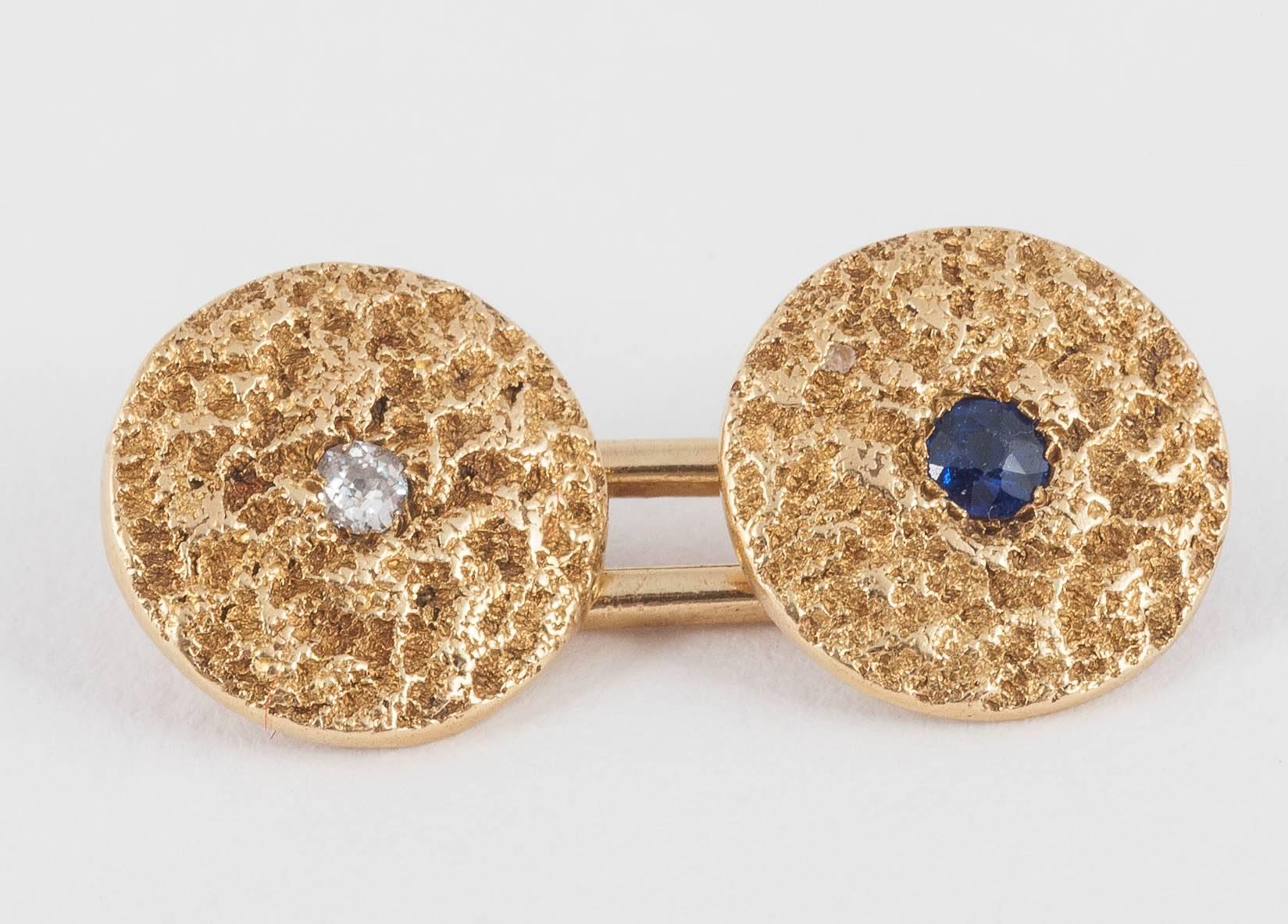 A heavy pair of 18ct [hallmarked] gold cufflinks of textured nugget design,two sides set with a ceylon sapphire,two sides with an old cut brilliant diamond.English c,1900-10
