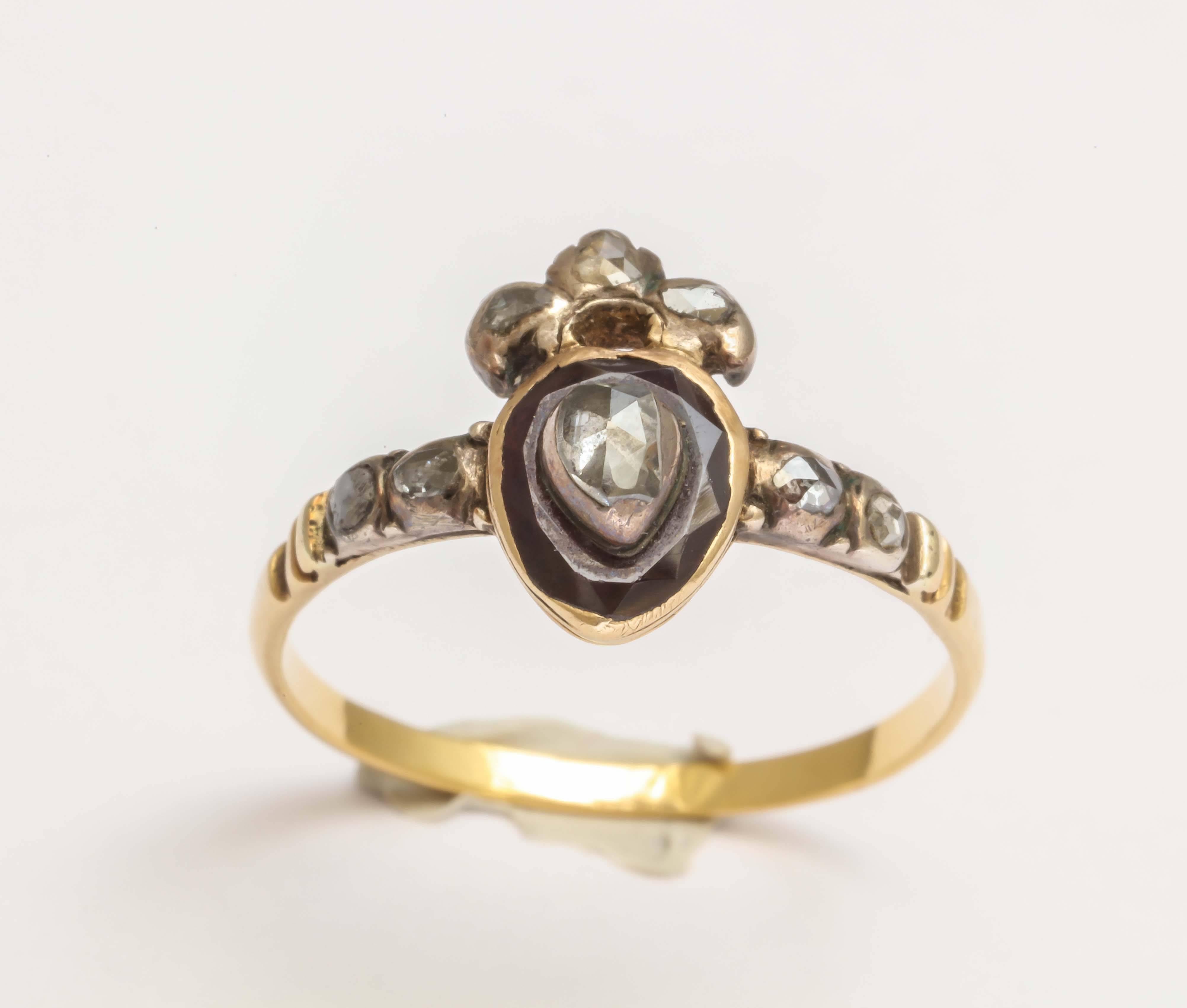 Dating to around 1740, this incredible ring of English origin is designed as a crowned heart. This design symbolizing love and loyalty was a favorite of this period. A rose cut diamond is set into a garnet. Rose cut diamonds are set in the crown and