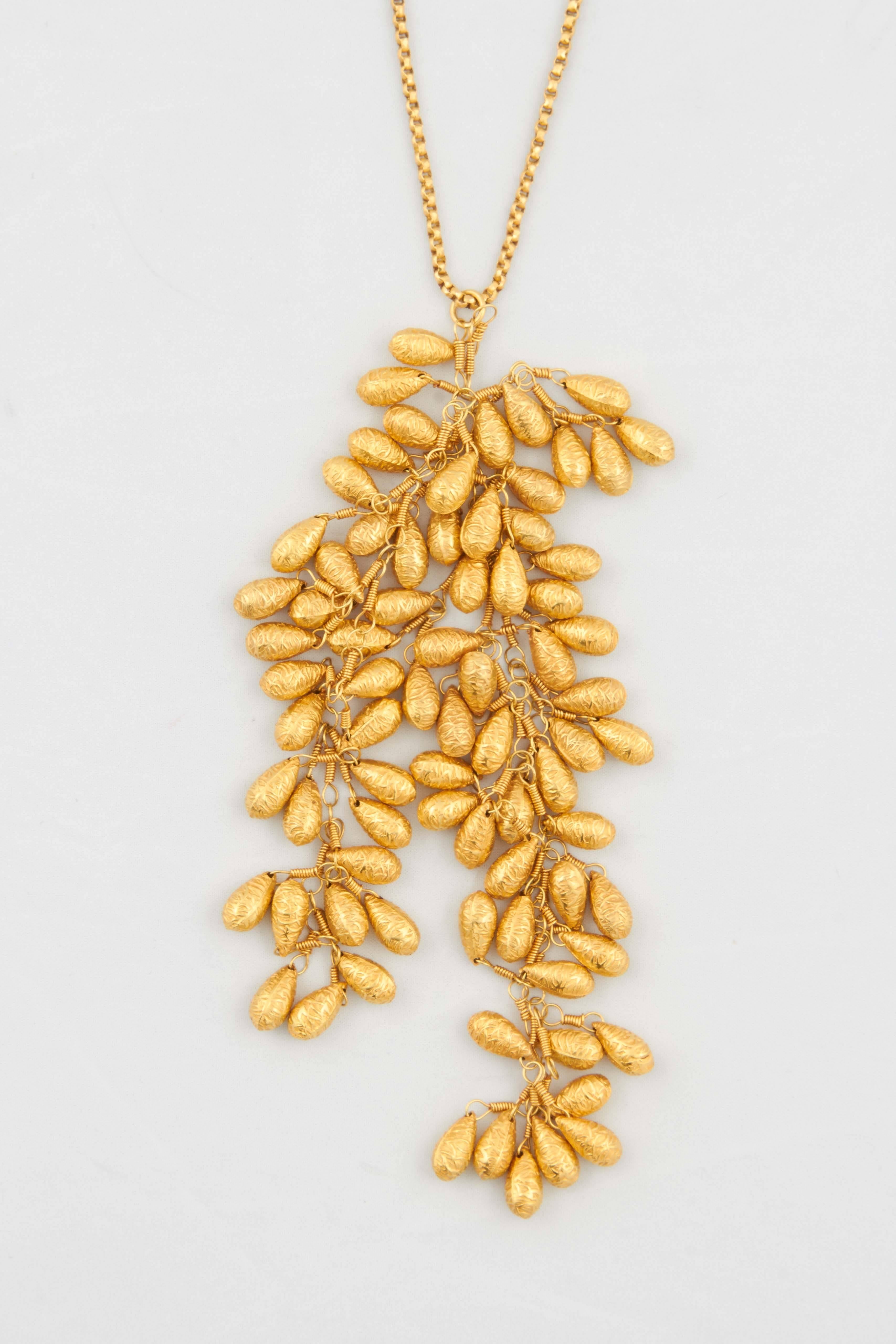 An 18kt yellow gold necklace composed of a cascading pendant containing two 18kt yellow gold grape vines. There are also two small cascading grape vines on either side of the clasp. The length of the chain is 23". The length of the necklace