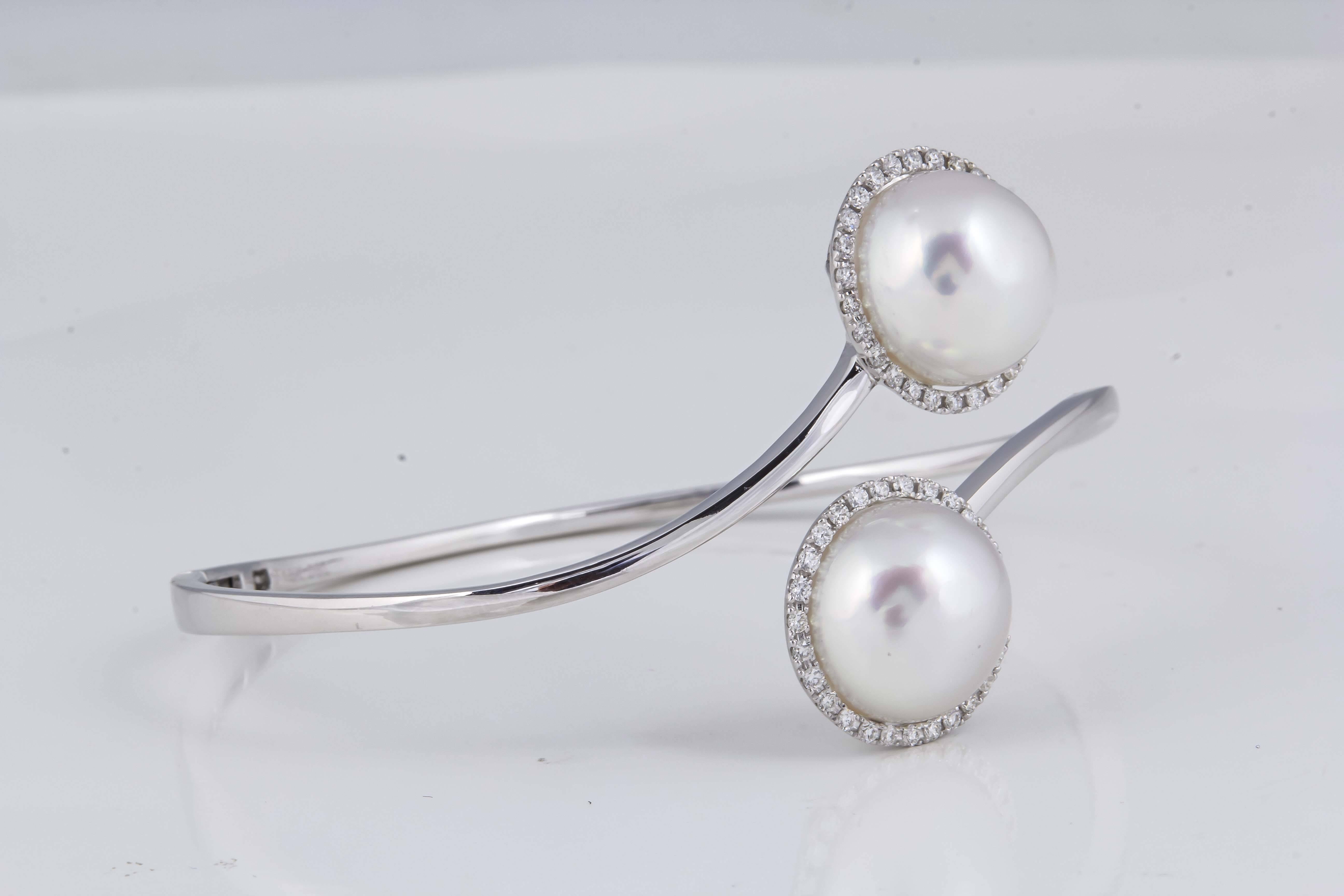18K White Gold bypass bangle bracelet featuring two South Sea Pearls each measuring 12-13 mm surrounded by a diamond halo weighing 0.51 carats. 
Color G-H
Clarity SI

Pearls can be changed to Pink, Tahitian or Golden upon request. Price subject to