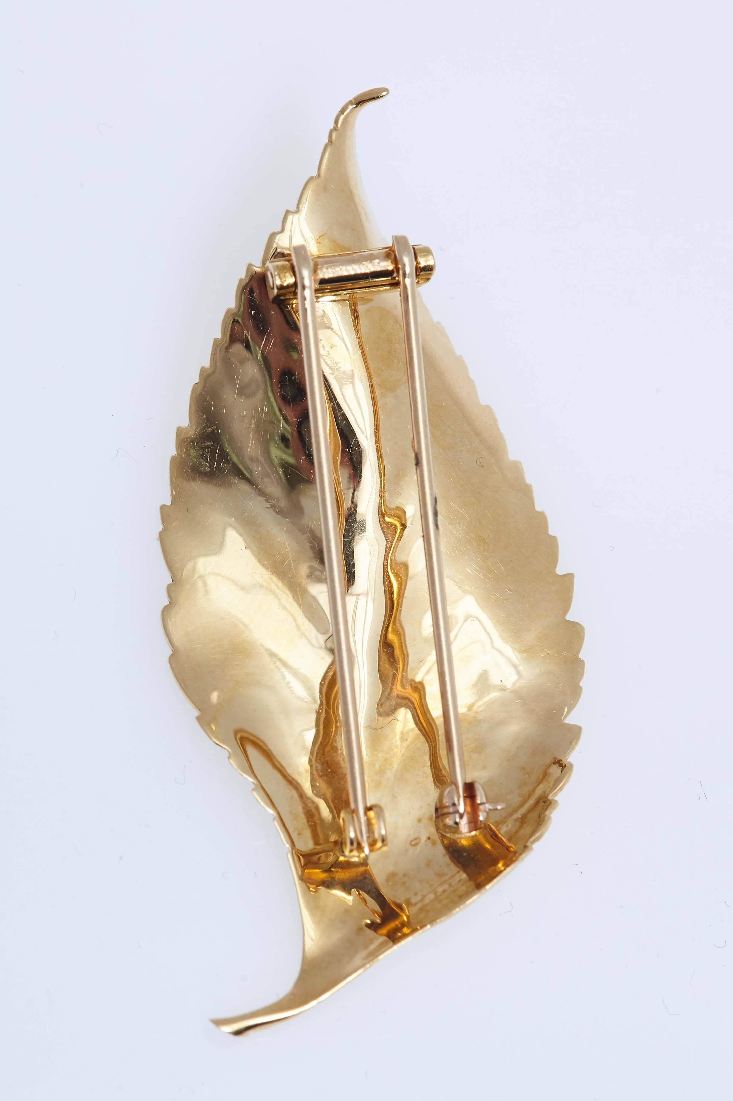 Cartier 18 karat yellow gold leaf pin.  The pin measures 2 1/2 inches long and 1 1/4 inches in width at its widest point. Stamped "CARTIER".