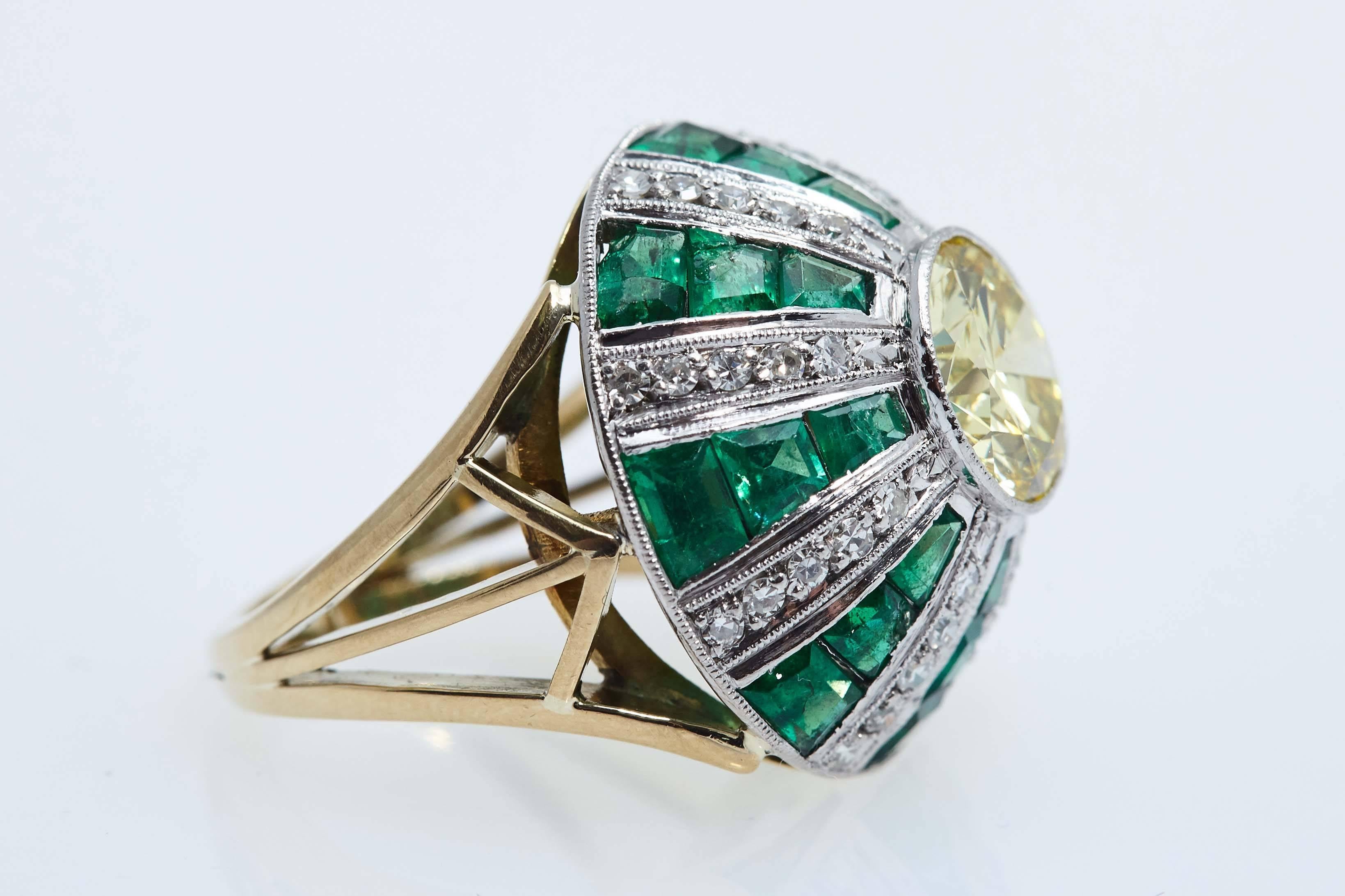 Round diamond weighing 2.62 carats in the center, GIA certificate Fancy Yellow and SI1 in clarity.  The ring has a dome design with emeralds and diamonds going up towards the center diamond. The ring measures 7/8" across at its widest point and