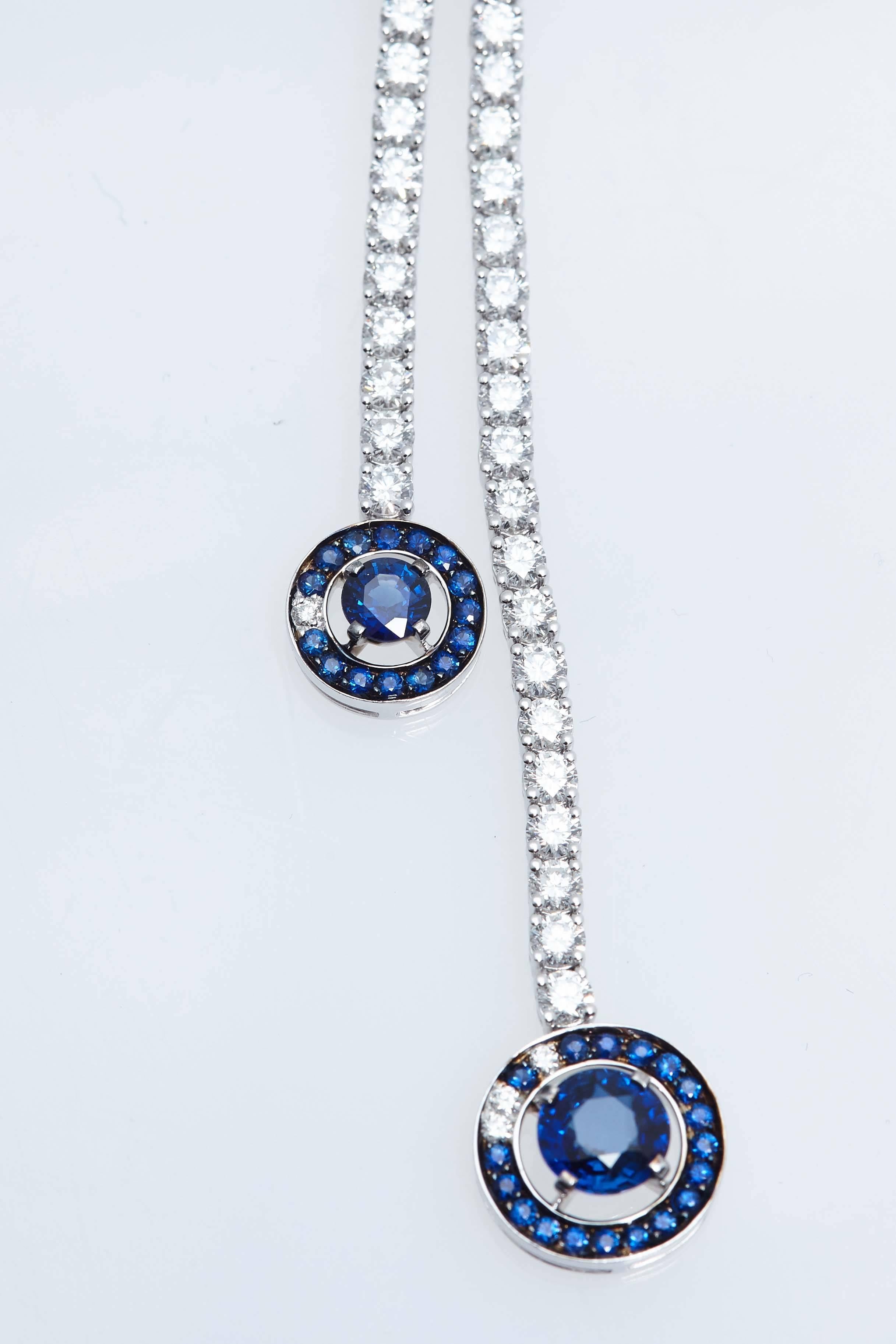 Boucheron diamond lavalier eighteen karat white gold necklace composed of round diamonds ending in two graduated sapphire pendants composed of a center sapphire stone surrounded by a ring of sapphires.  The neck portion measures 14 1/2 inches to the