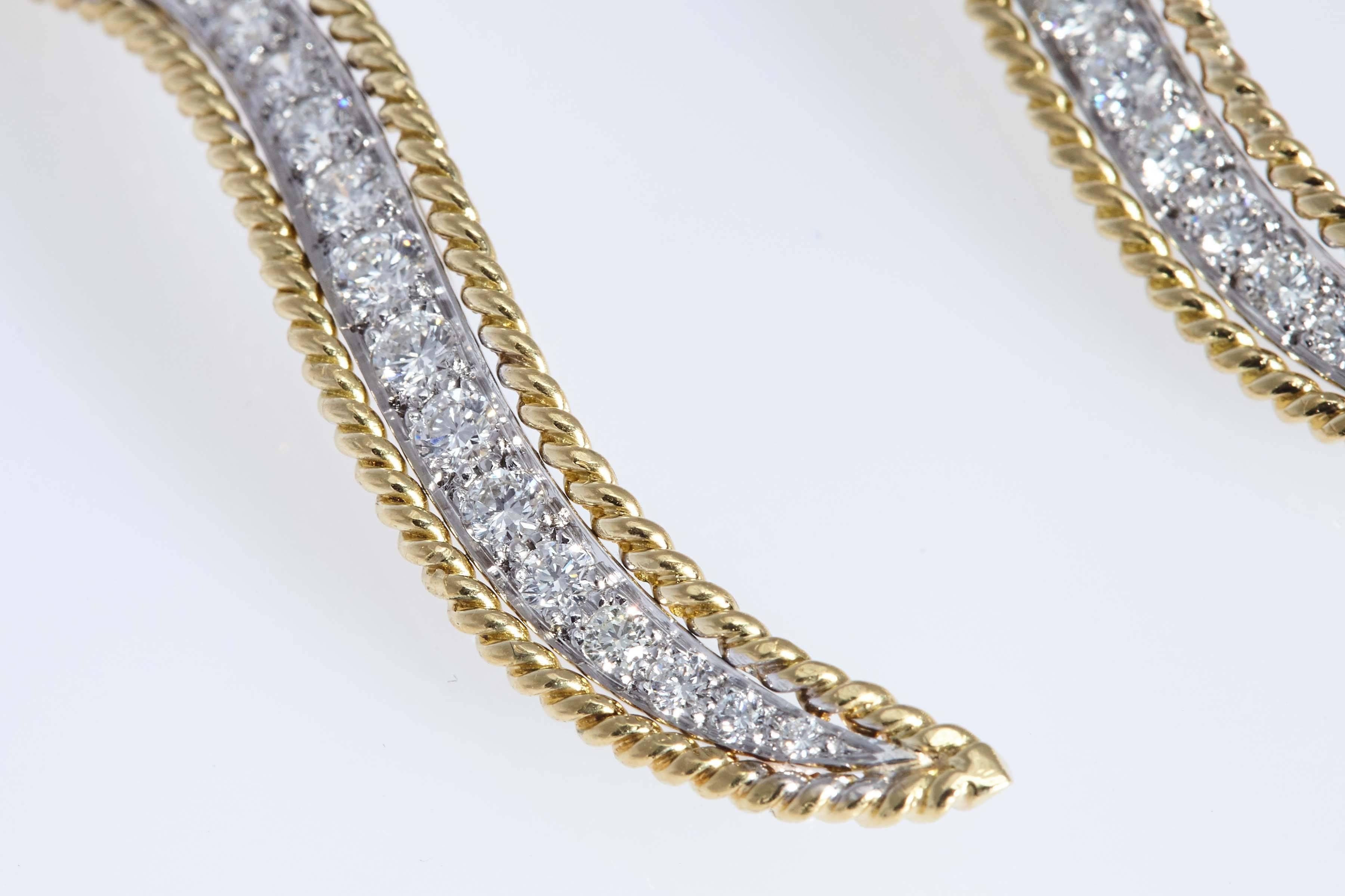 Two 18 karat white and yellow gold and diamond leaf pins  Each pin contains 17 round diamonds of graduated size which are set in white gold.  The perimeter of the pin is yellow gold which has a twisted rope design. The total weight of diamonds in