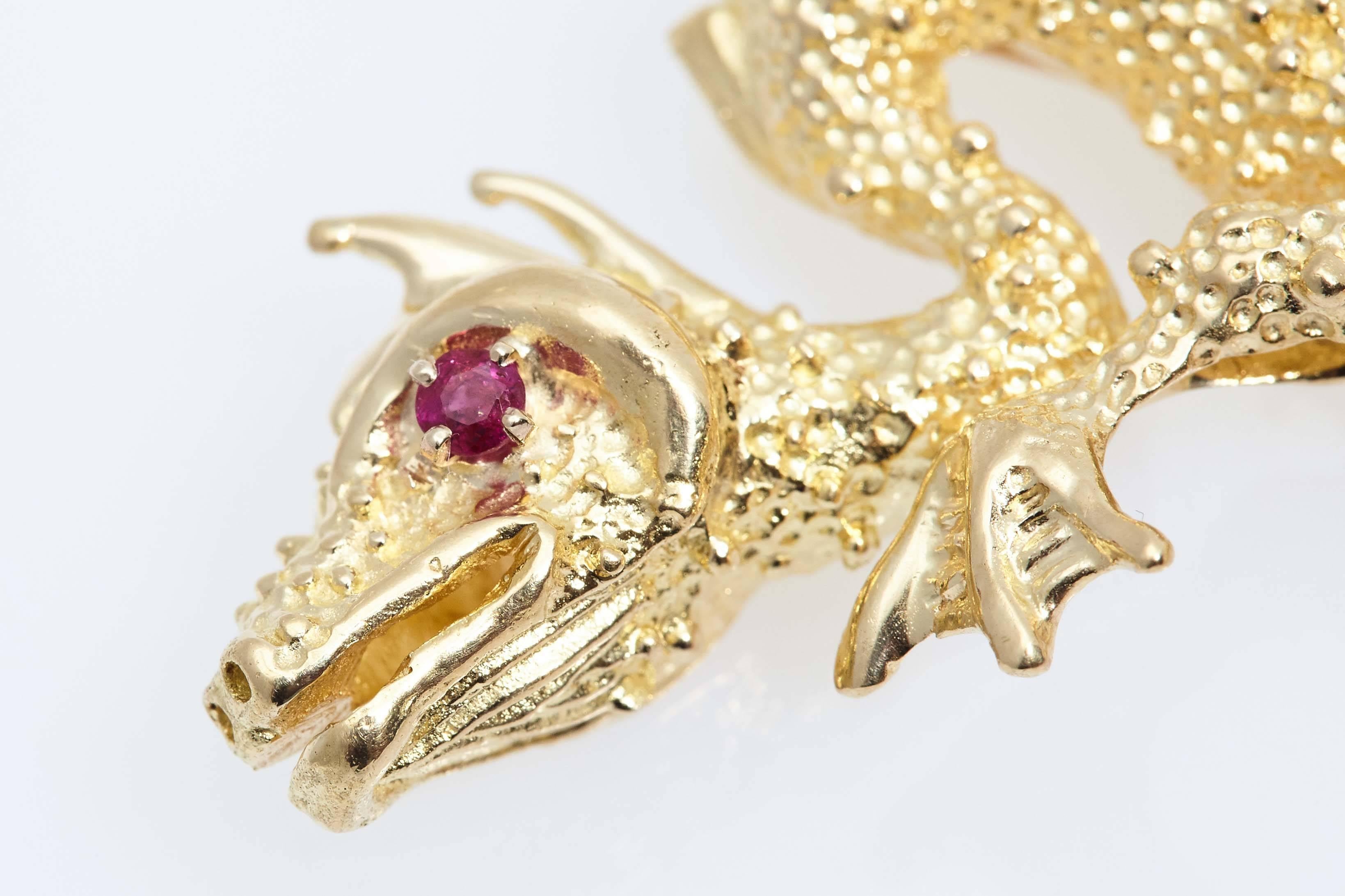 Van Cleef & Arpels eighteen karat yellow gold dragon brooch containing a round ruby eye.  The ruby weighs approximately .12 carat.the brooch measures 3 1/8 inches long and approximately 1 3/4 inches from top to bottom. It is marked "VCA and
