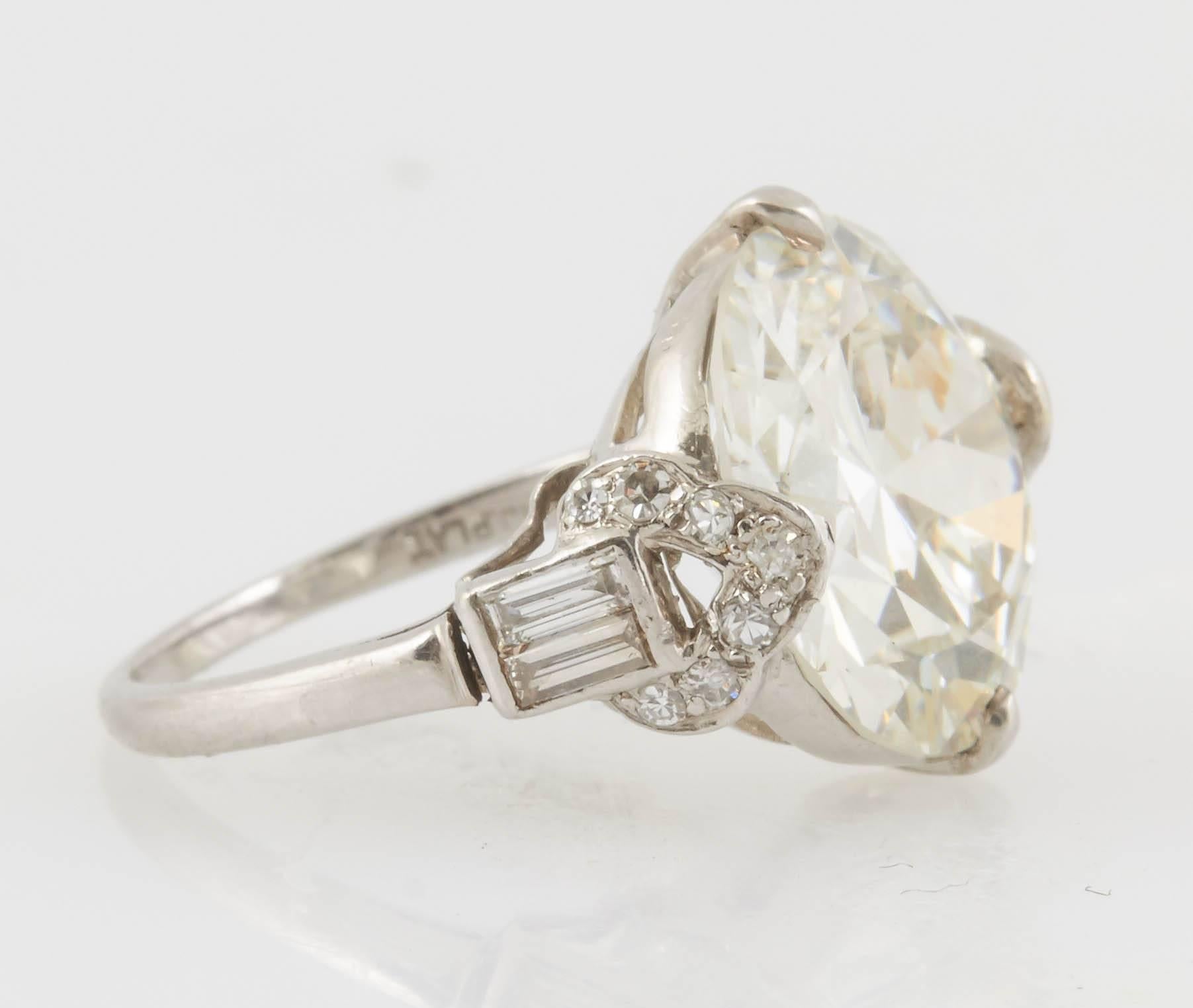 Antique Art Deco engagement ring, finely crafted in platinum, with GIA certified Old European cut diamond at the center, weighing 7.12 Carat, J color VS2 clarity. Accenetd with baguette and single cut diamonds. 