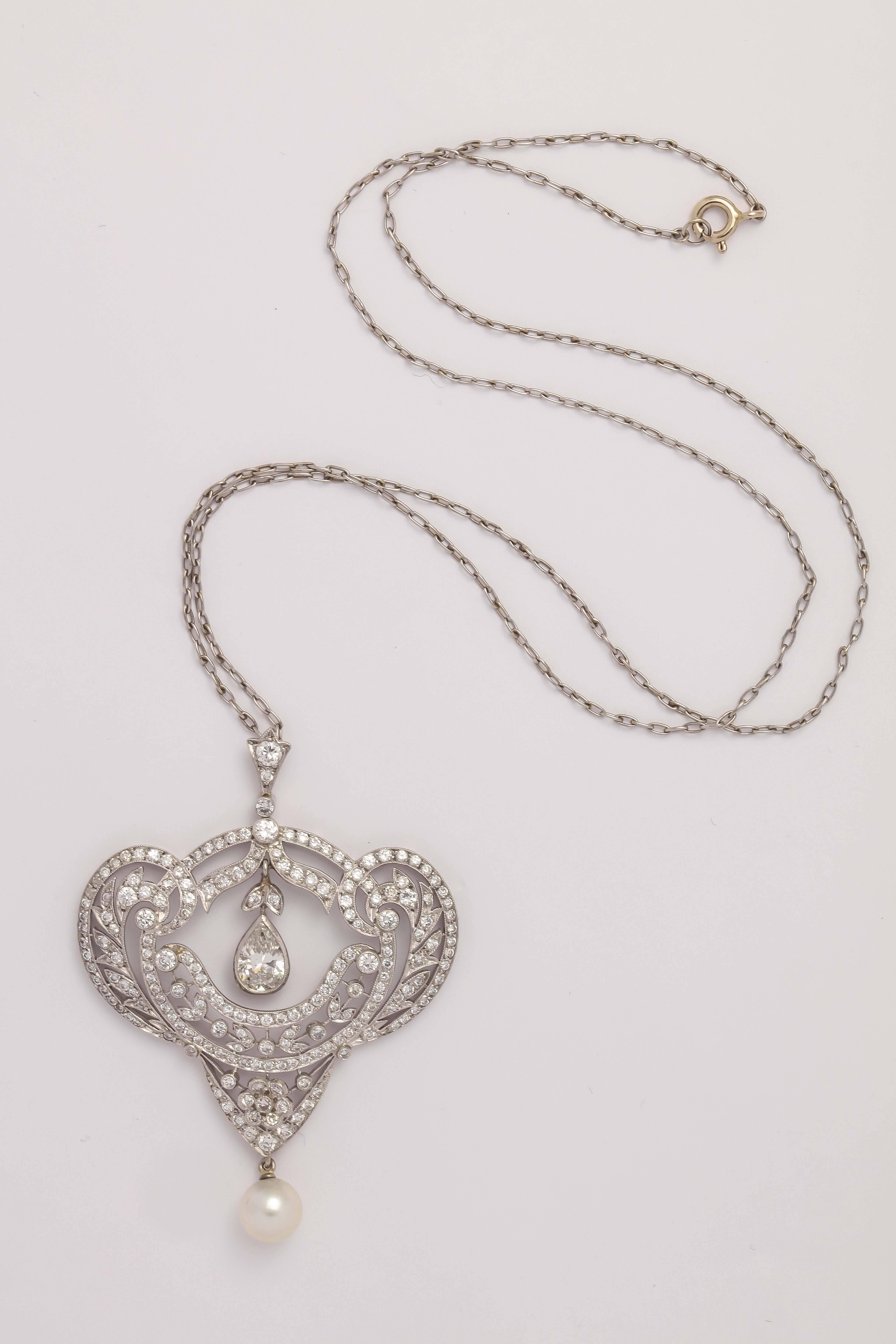 Beautiful Platinum, Diamond and Pearl Pendant on simple  Platinum Chain.
Pendant hangs from a Diamond set bale and is of foliate design. There is a Pear shaped bezel set Diamond floating within the pendant and it weighs just under 1 carat. Very