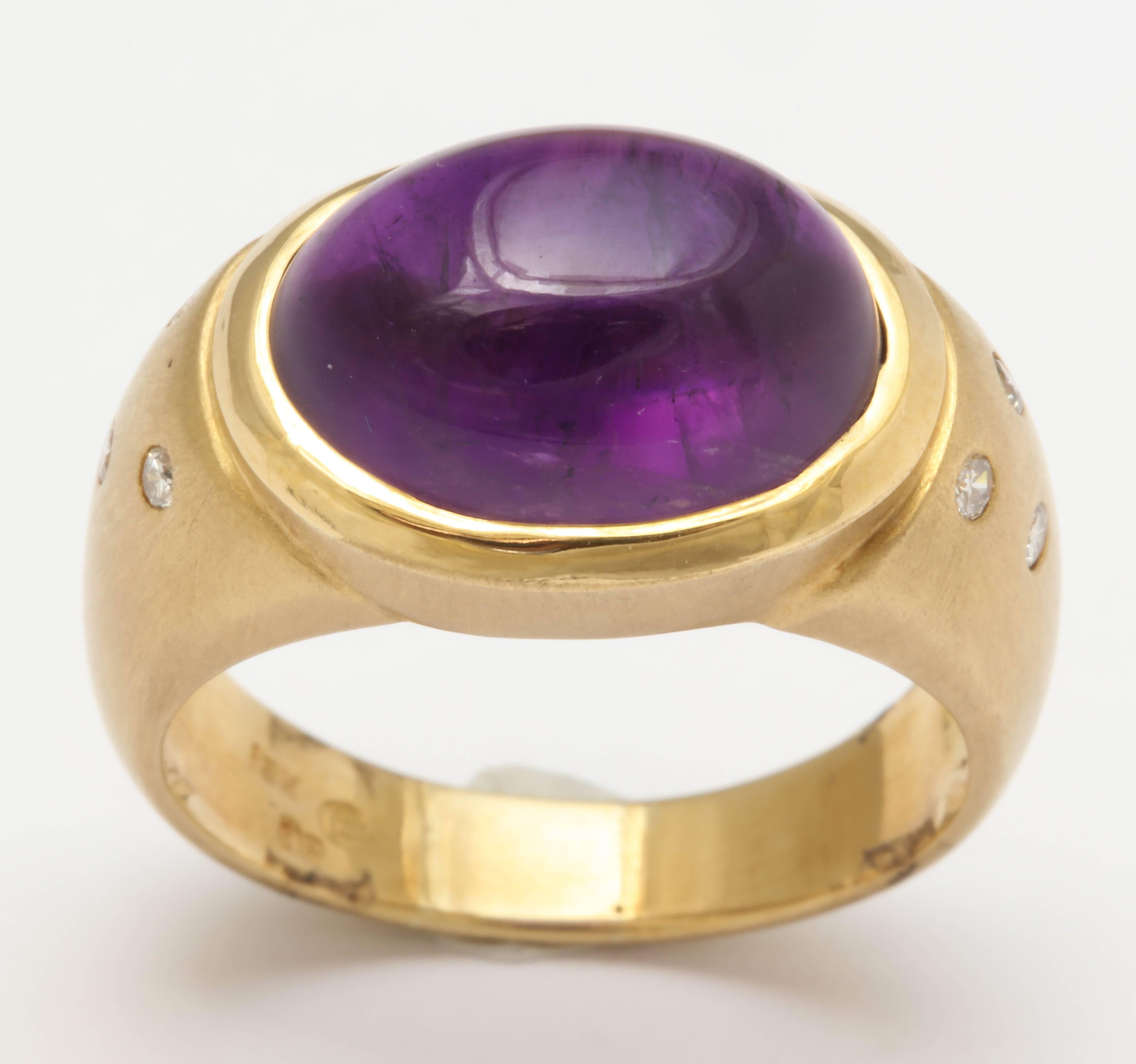 This oval cut cabochon rich purple amethyst is bezel set in a classic style 18 kt ring. The  diamonds are ' gypsy' set on either side of the center stone. The gold is matte finished and makes the diamonds pop. The ring is 8 1/2 and can be sized. It