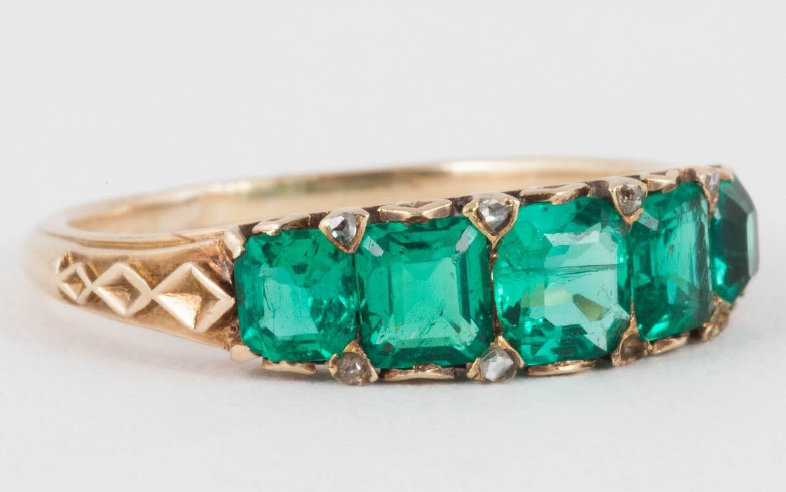 A fine quality columbian emerald 5 stone half hoop ring with carved gallery,and set with rose cut diamonds.English c,1880