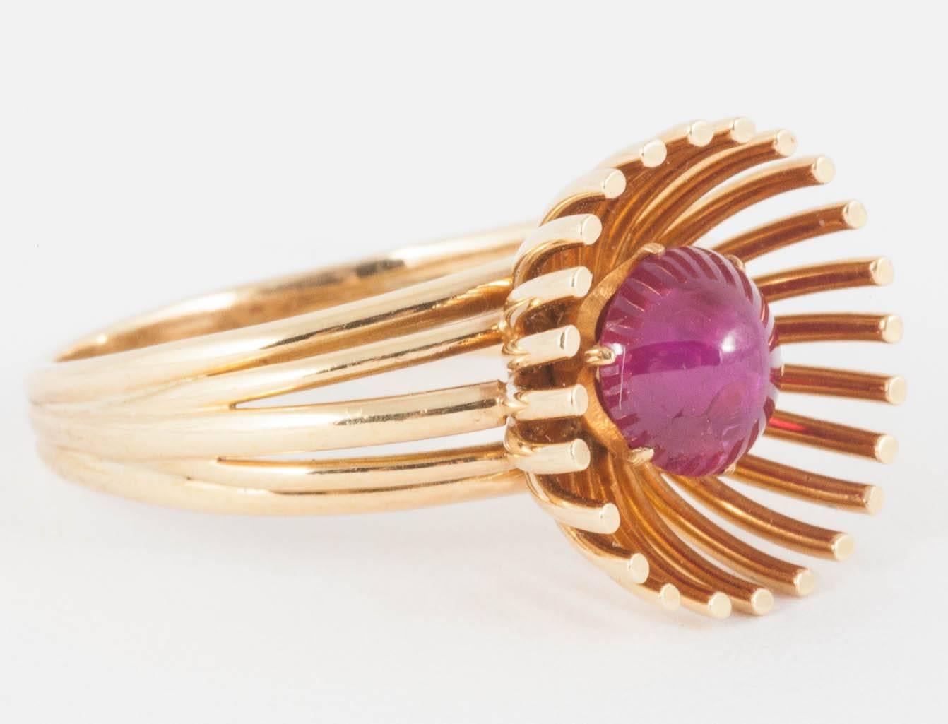 An unusual 18ct yellow gold ring of wirework design,with a cabochon cut burma ruby centre stone protected by its petalled surround,hallmarked london 1954 and signed Hans Mautner