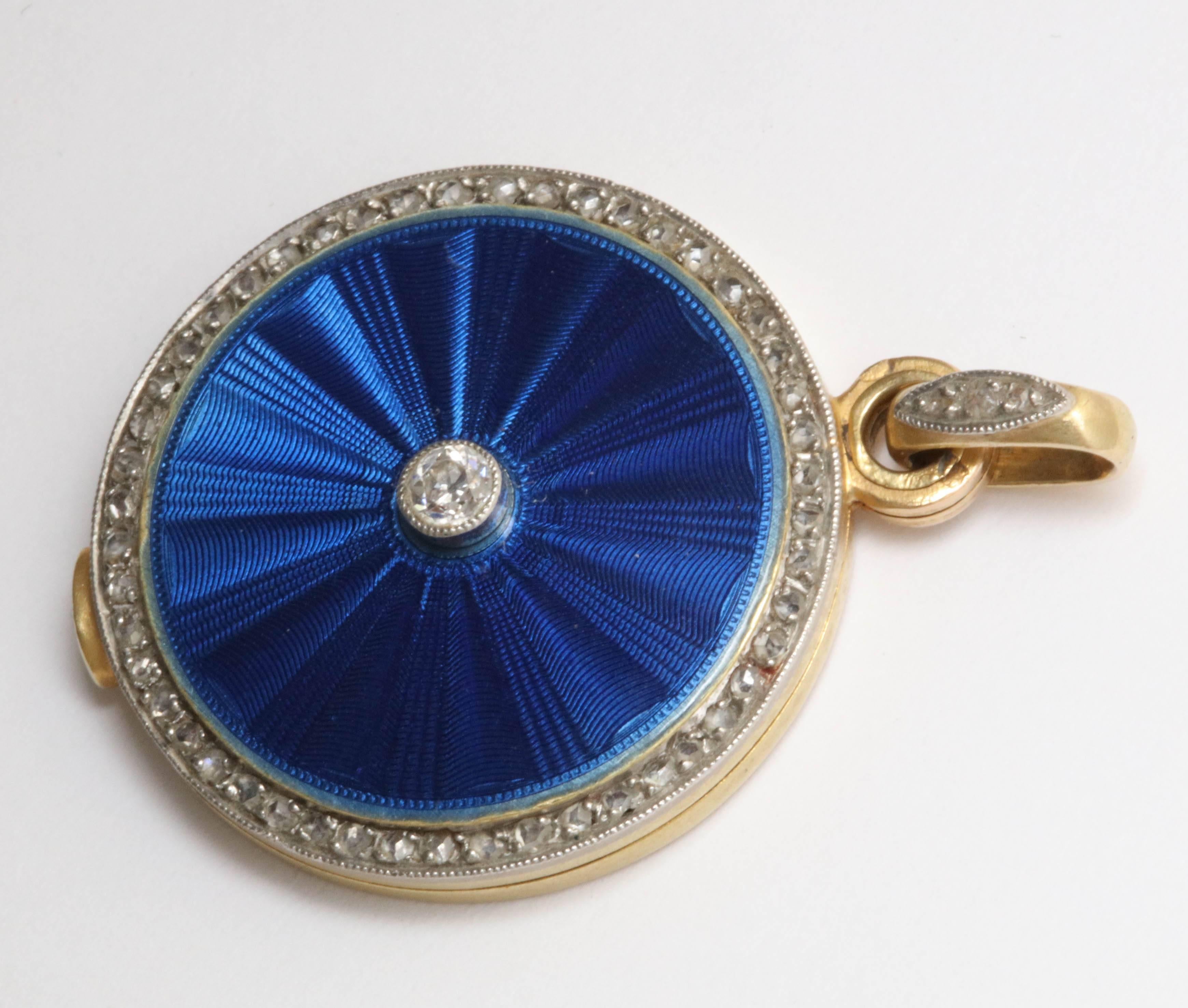 One Ladies  Flat And sleek Slide Locket Decorated With A Sunburst Design Guilloche Royal Blue Enamel In The Center Of Locket. Further Embellished With Numerous Rose Cut Diamonds Around The Border Of The Locket,. One Antique Cut Old European Cut