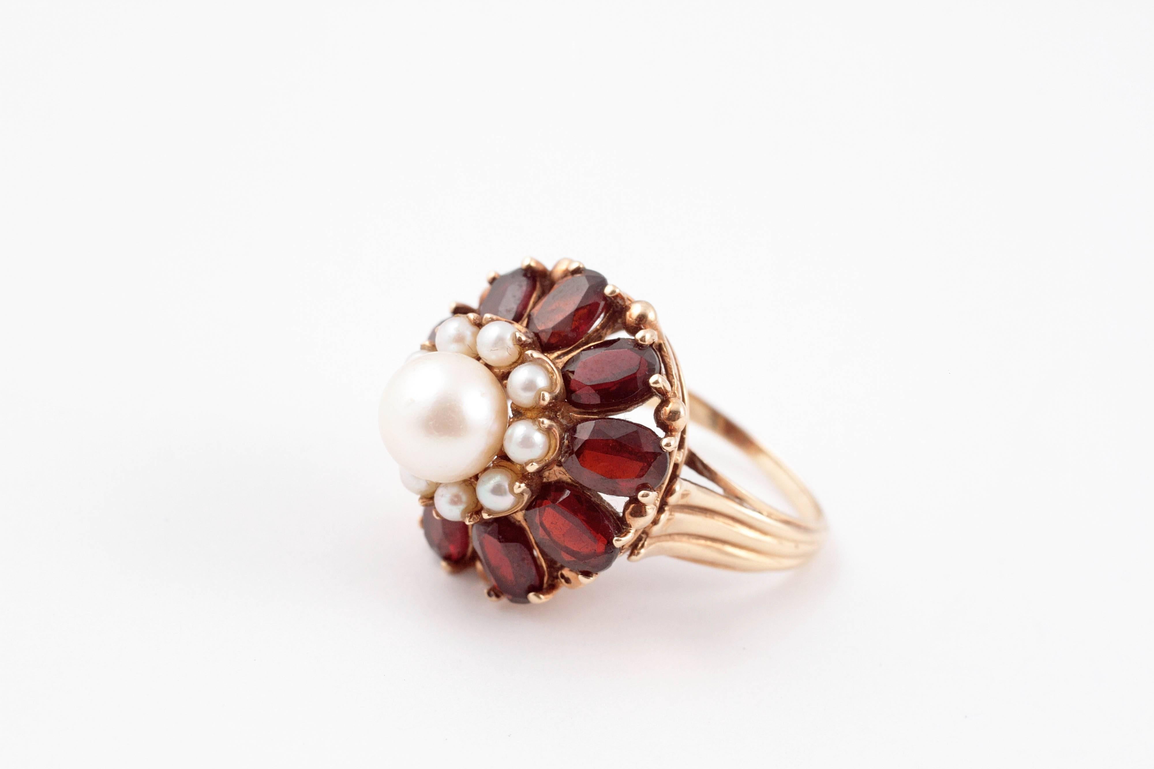 Cultured pearls surrounded by garnets in a delightful flower flower ring style.  The large pearl measures 7.25 mm and all are set in 14 Karat yellow gold.  Size 7 1/4.