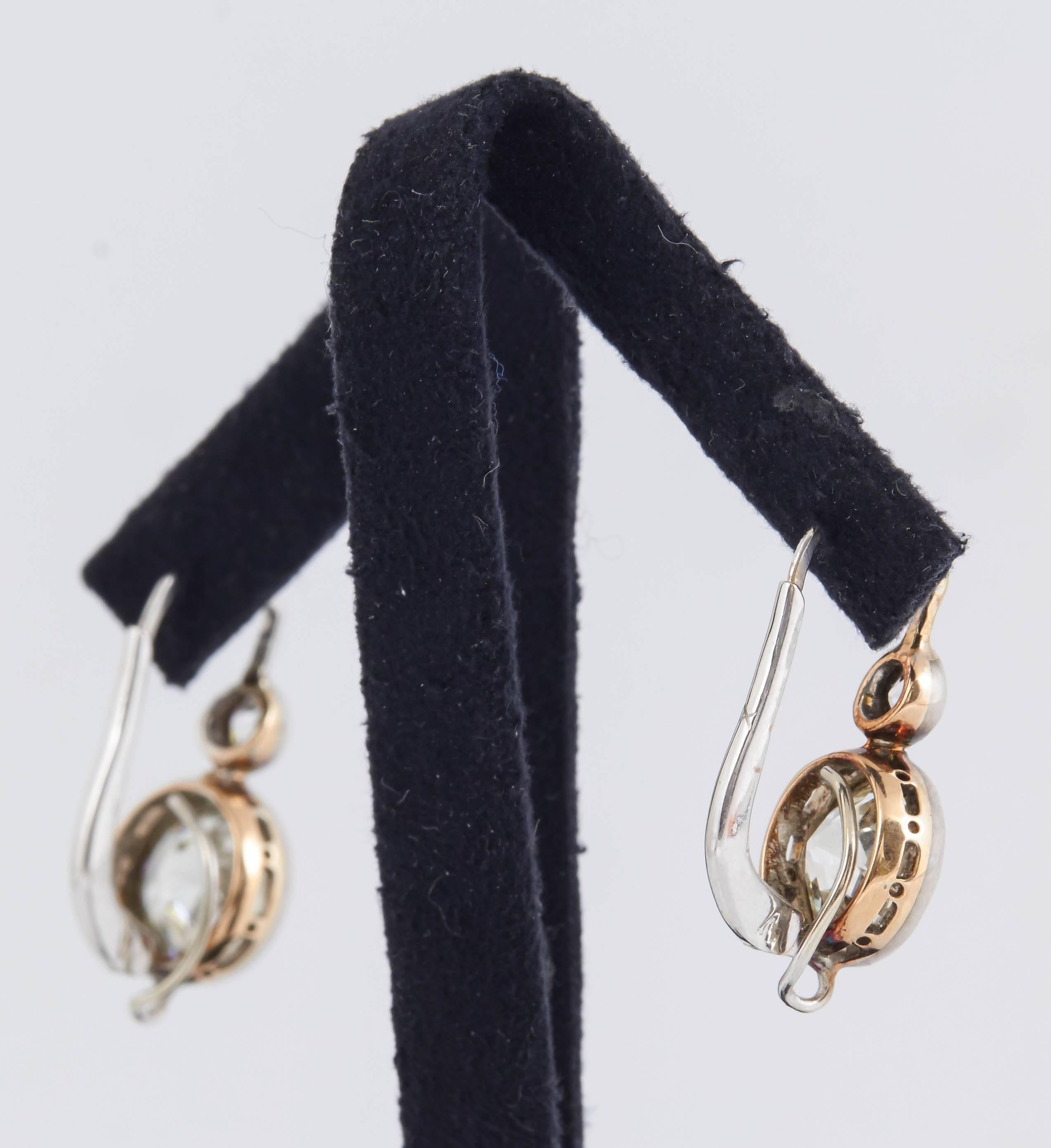 Art Deco two stone earrings backed in gold and topped in platinum. Each earring centers 1 larger old European-cut diamond suspended from 1 smaller old European-cut diamond. Larger Stones weigh a total of 7.00 carats, smaller stones weigh a total of