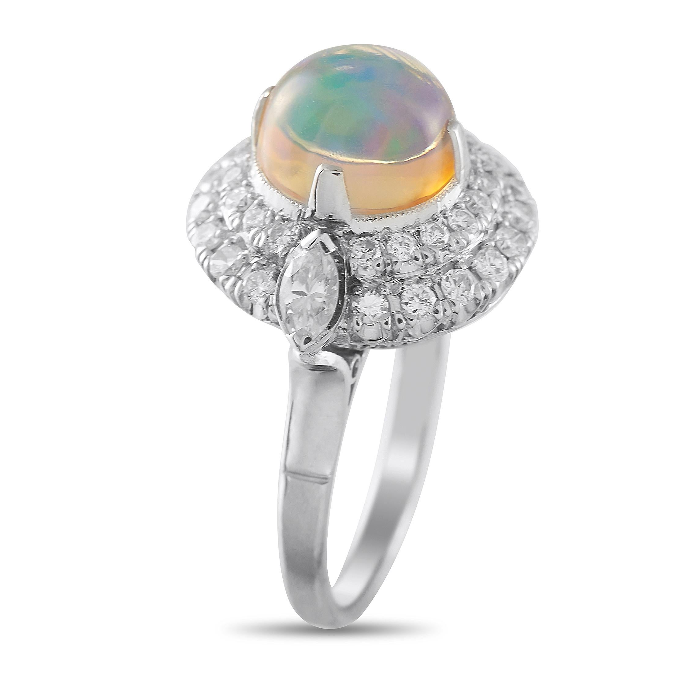 Un anello che cattura l'incantevole bellezza degli opali. Questo anello in platino mette in mostra uno splendido opale cabochon, dalla forma arrotondata e a cupola, intrigante nel suo gioco di colori. Attorno ad esso c'è una doppia aureola di