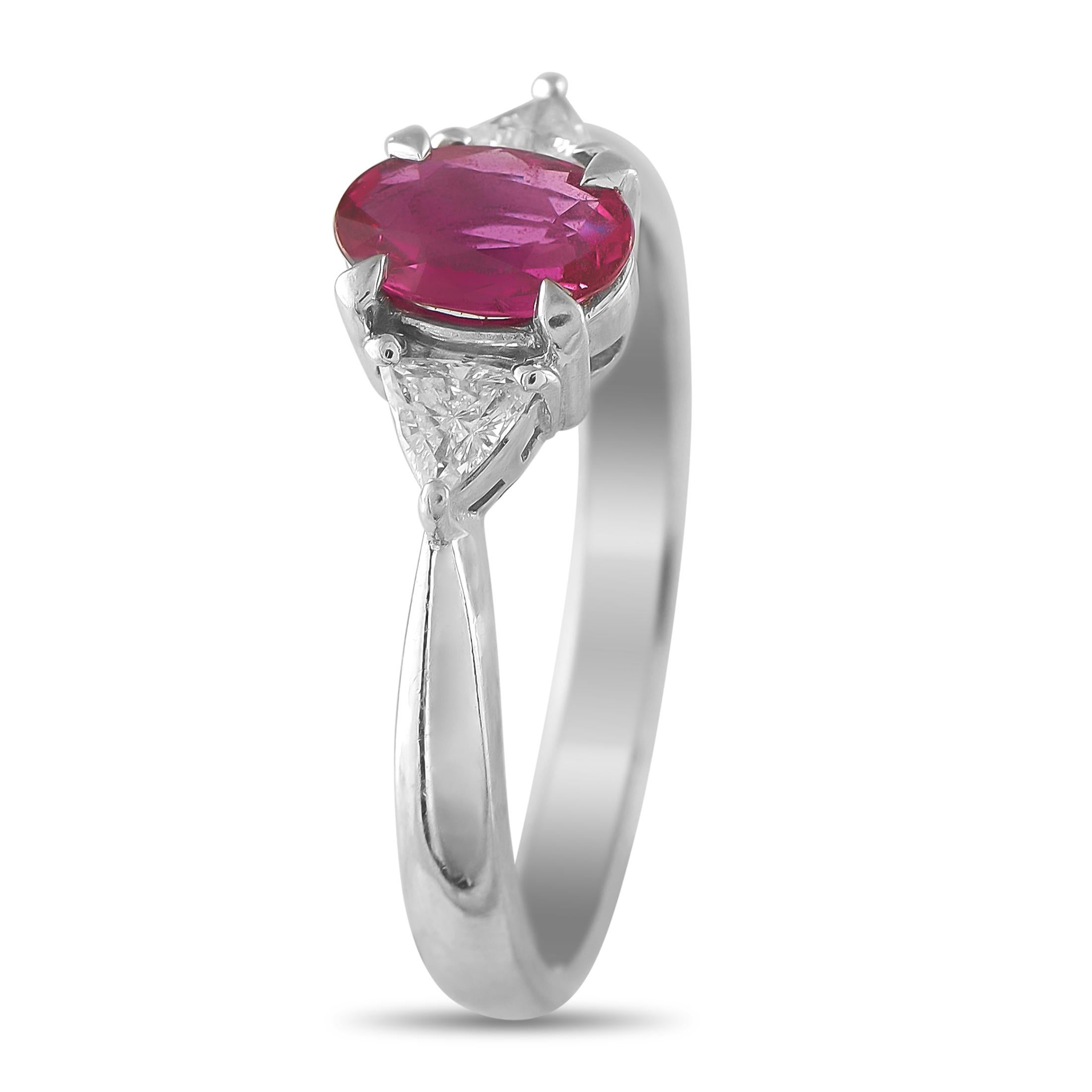 Dove il colore sorprendente incontra la forma raffinata. Questo anello in platino presenta una fascia sottile che racchiude un trio di pietre: un rubino dal taglio ovale al centro, affiancato dall'eleganza geometrica dei diamanti dal taglio