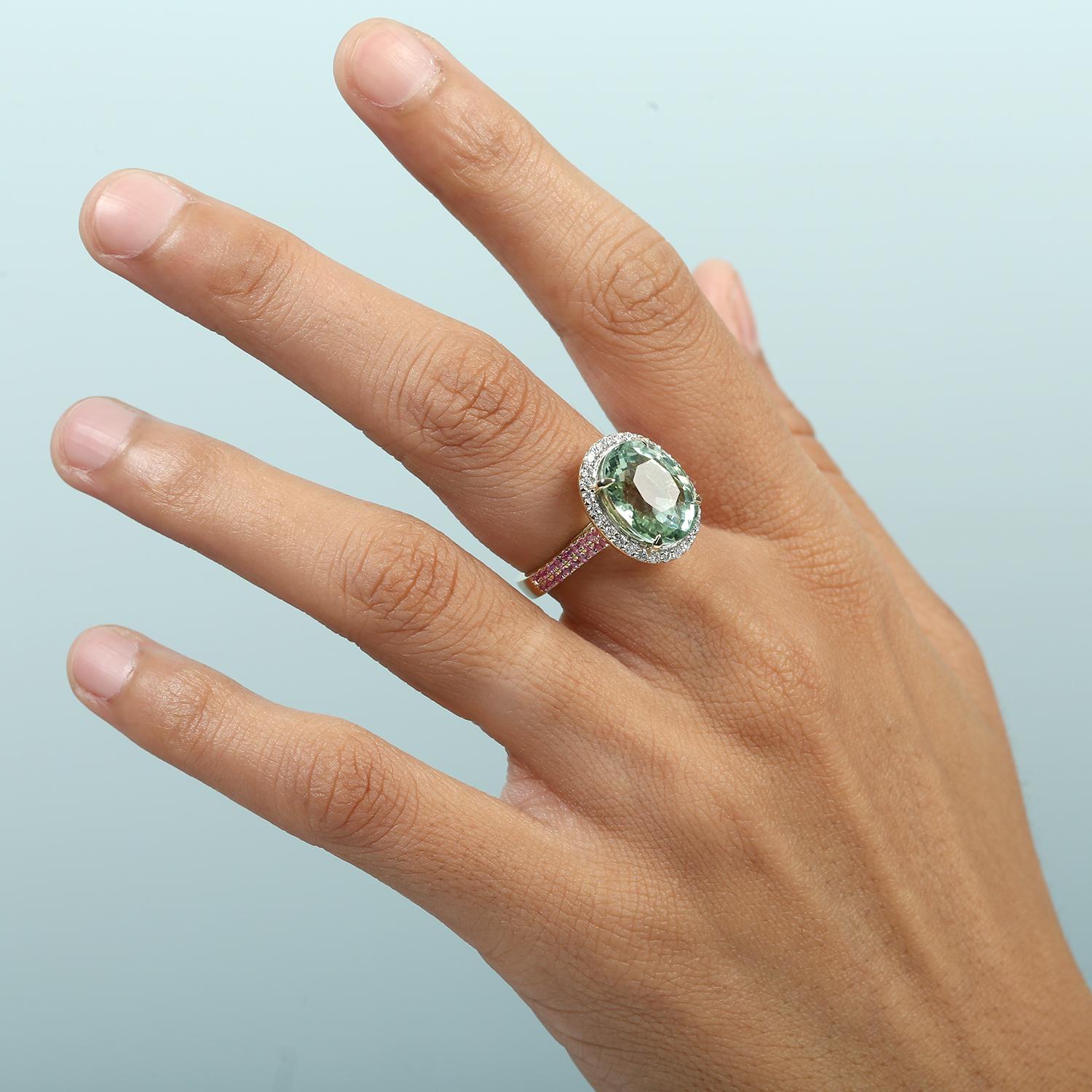 Fusion vibrante de couleurs et d'élégance, cette bague de cocktail présente en son centre une tourmaline menthe lumineuse, flanquée de saphirs roses vifs et encadrée de diamants pavés étincelants. Réalisé en or jaune 14 carats, il s'agit d'une pièce