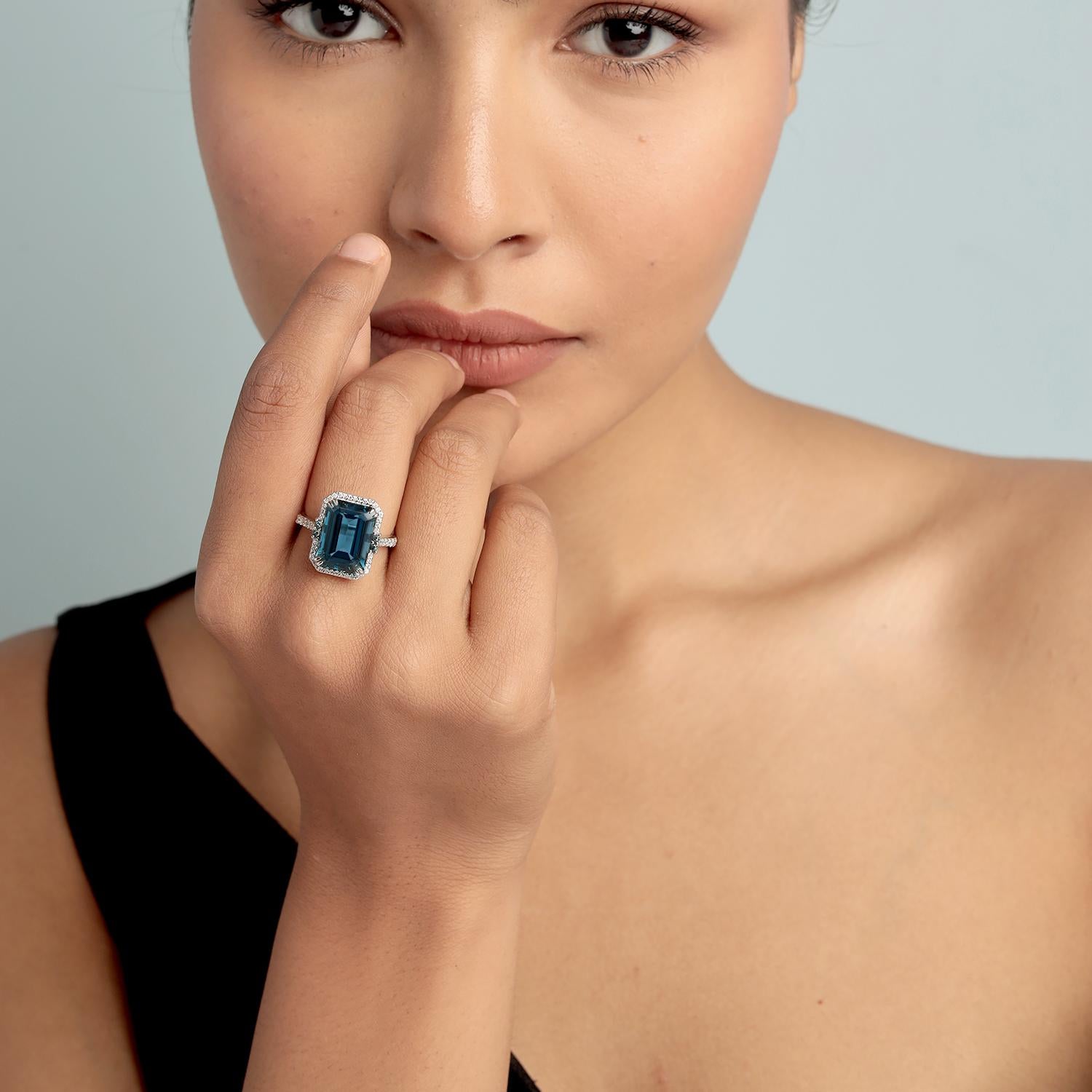Faites une déclaration raffinée avec cette bague magnifiquement structurée, ornée d'une topaze bleue de Londres de forme octogonale. Monté en or blanc 14 carats et rehaussé de diamants étincelants, ce modèle allie des lignes épurées à des couleurs