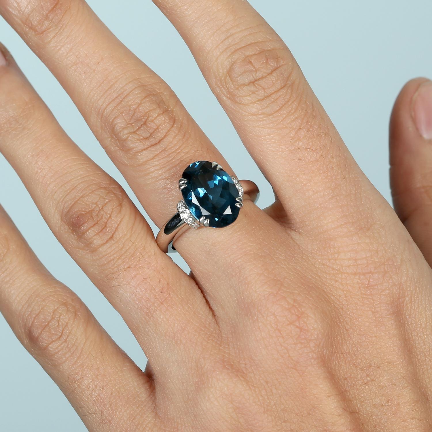 Elegante e accattivante, questo anello presenta un Topazio Blu di Londra dalla forma ovale ricca di sfumature, delicatamente accentato da diamanti scintillanti. Realizzato in oro bianco 14KT, offre un design senza tempo con un tocco moderno -