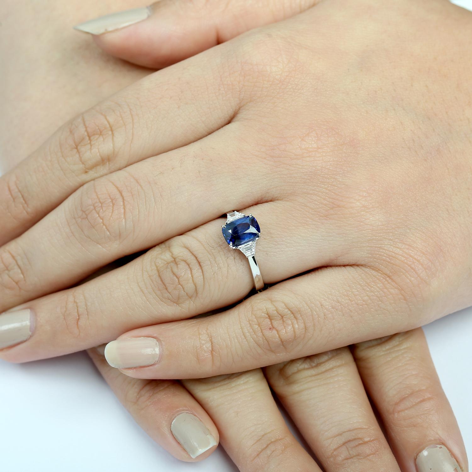 Dieser schlichte und doch luxuriöse Ring zeigt einen blauen Ceylon-Saphir im Kissenschliff, der durch eine raffinierte Anordnung von Diamanten veredelt wird. Er ist aus glattem 18-karätigem Weißgold gefertigt und bietet eine perfekte Mischung aus