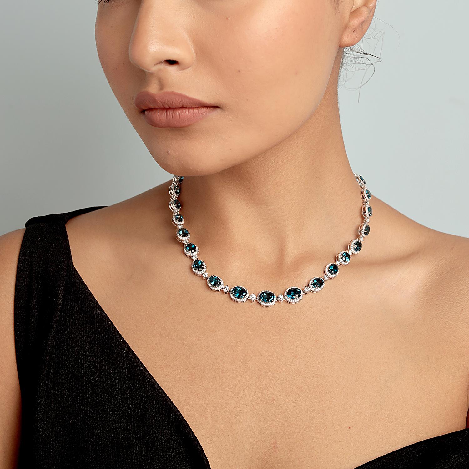 Fai un'entrata scintillante con questa lussuosa collana con uno splendido Topazio Blu di forma ovale circondato da diamanti abbaglianti. Realizzato con maestria in luminoso oro bianco 14KT, questo pezzo audace è la miscela perfetta di grandezza e