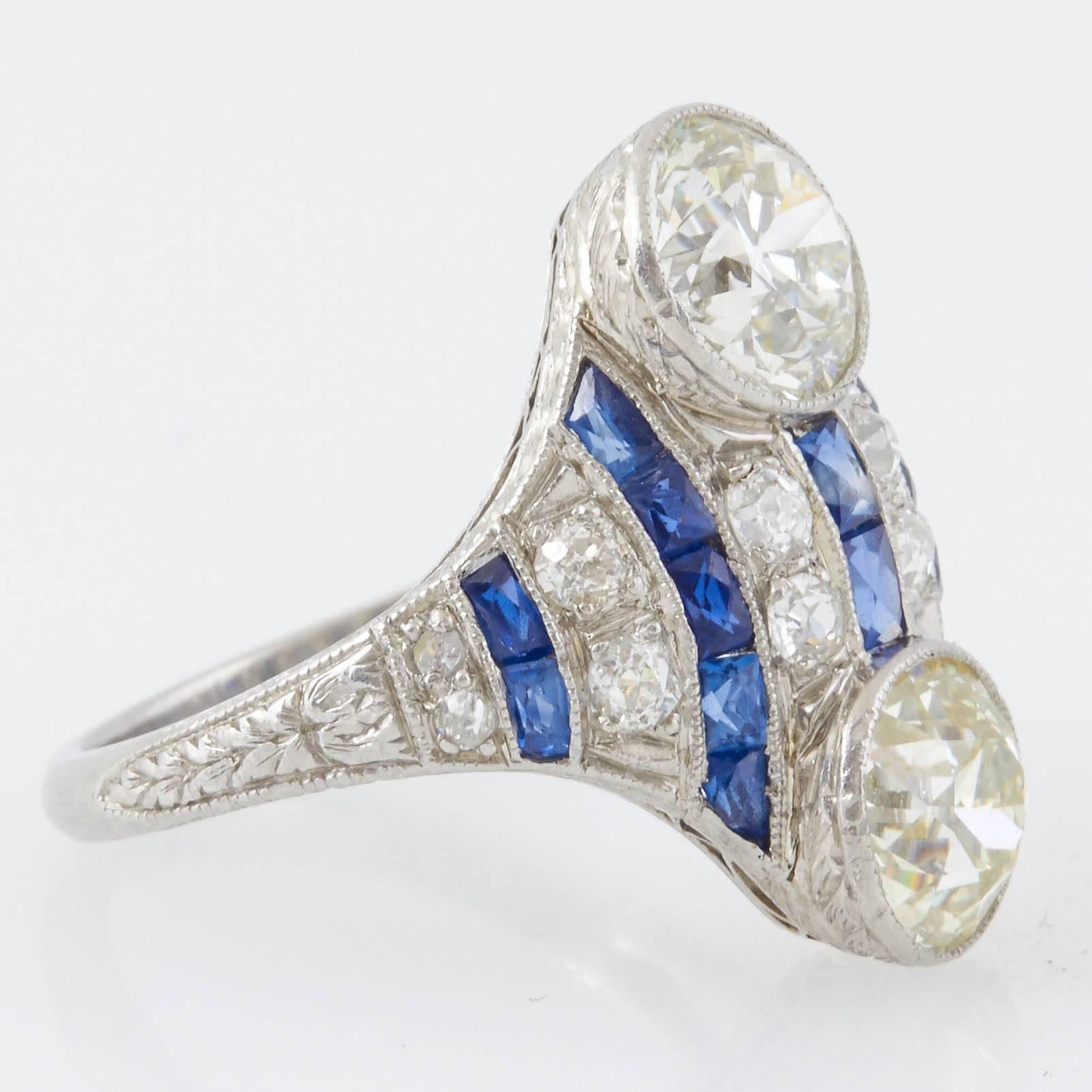 Original Art Deco dinner ring finely crafted in platinum features 2 large round cut diamonds and 12 smaller round cut diamonds weighing a total of approximately 3.00 carats. Vintage dinner ring is accented with 0.70 carat of sapphire. Ring Size US