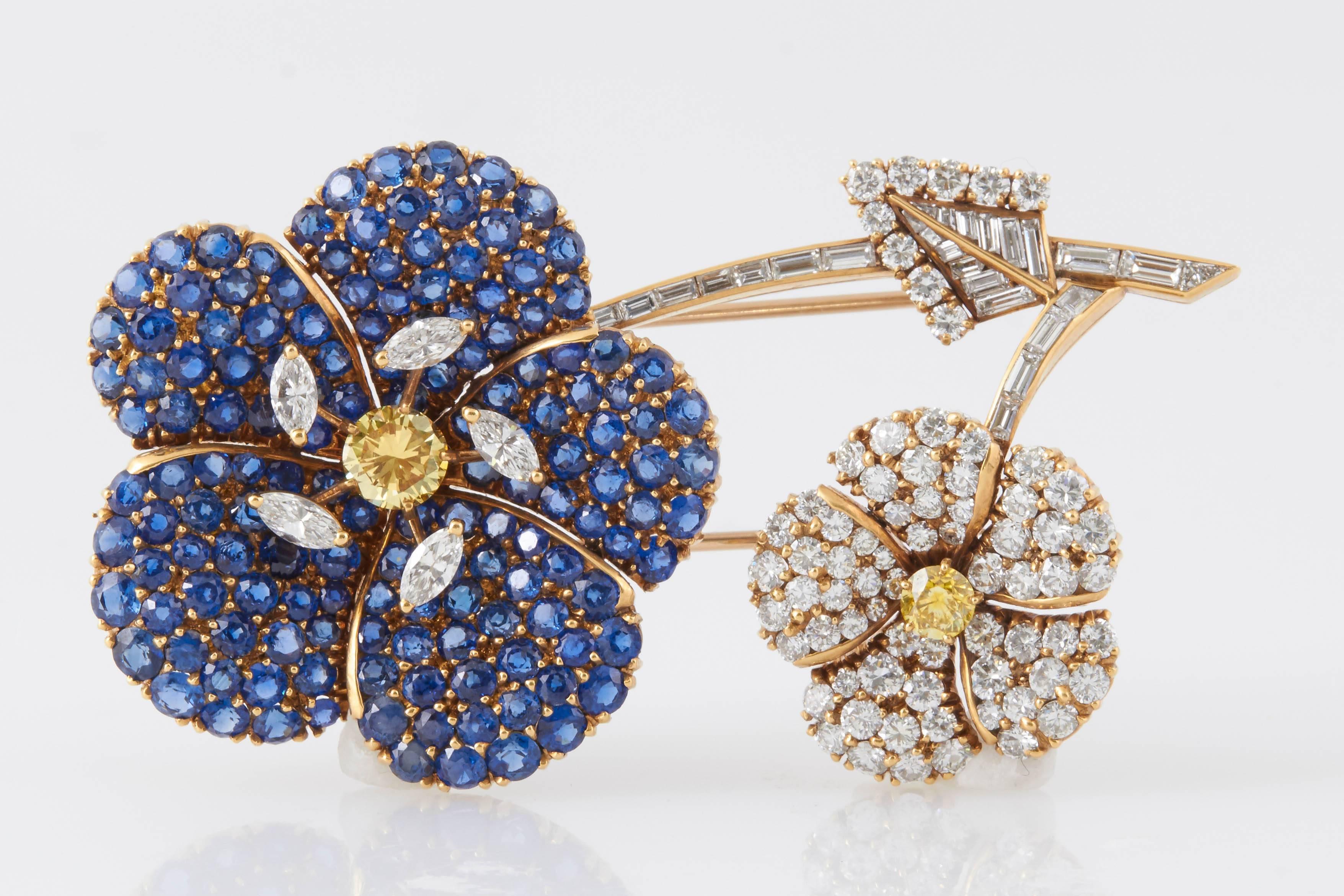 Signed Cartier Flower Brooch finely crafted in 18K yellow gold, accented with sapphires, natural fancy yellow diamonds, round and baguette cut diamonds. 