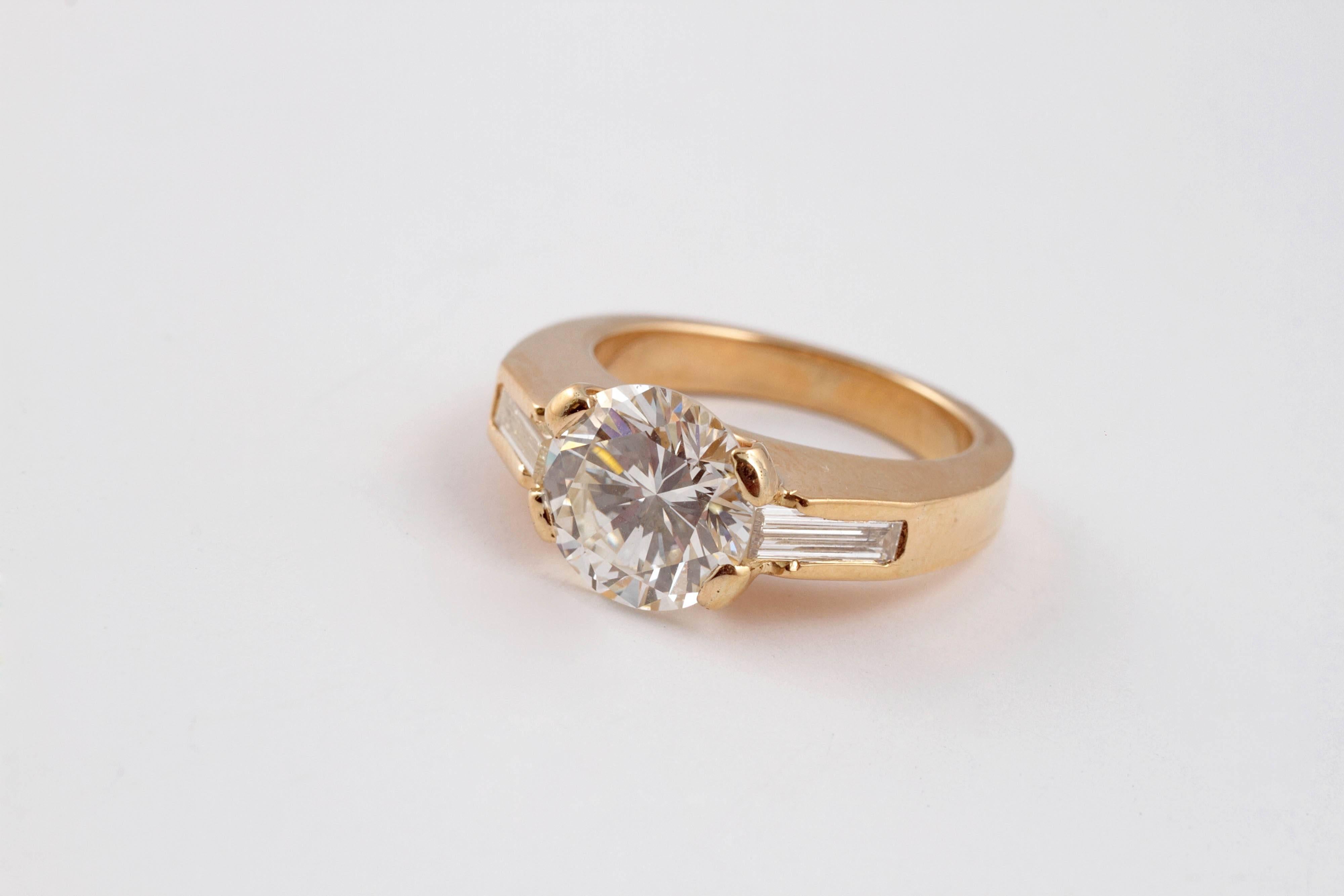 3.11 carat round diamond with baguette side stones in polished 18 Karat gold shank.  Size 6 1/2.