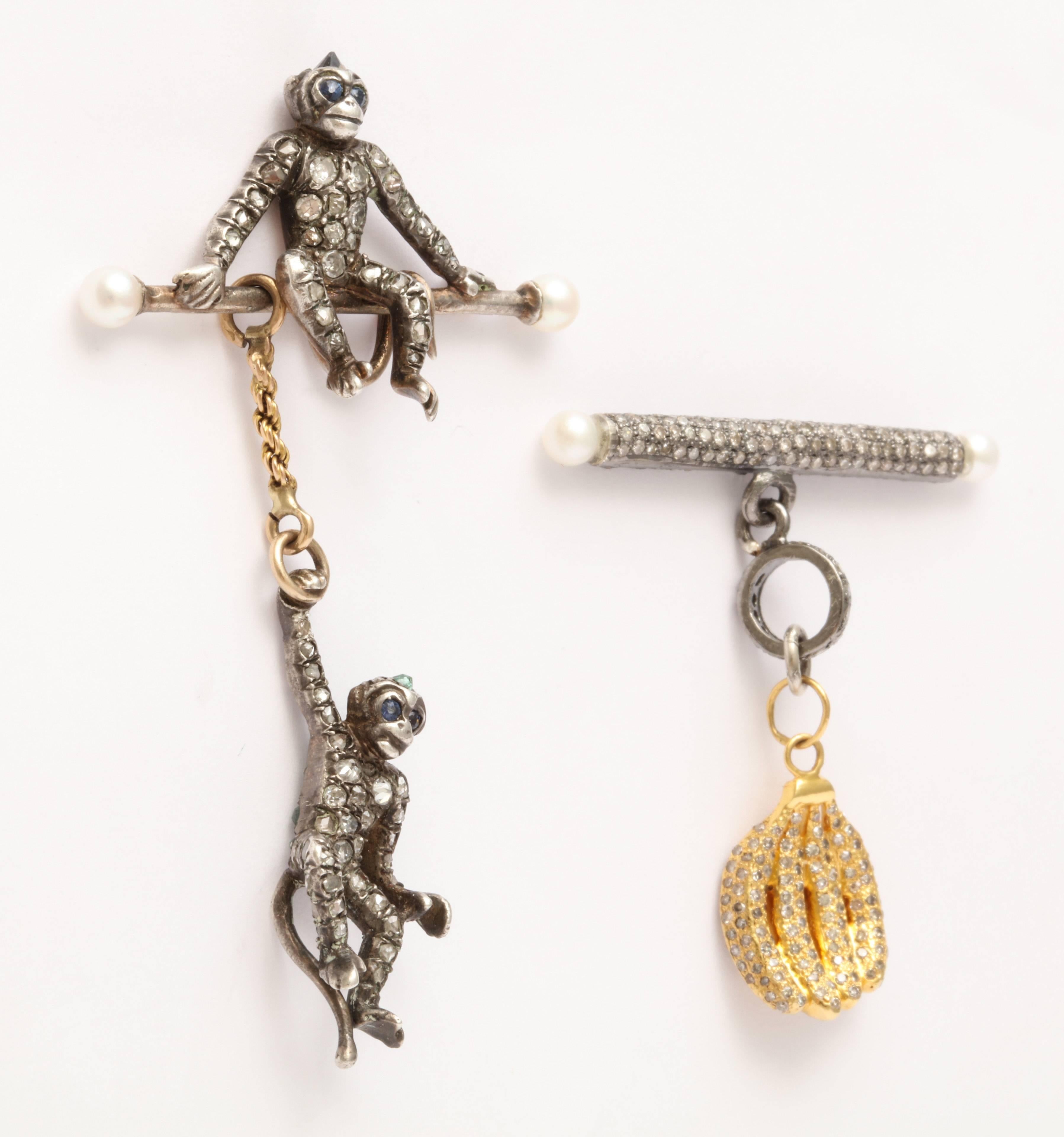 A pair of earrings composed of swinging monkeys and a bunch of bananas.
The 18kt yellow gold bananas are set with diamonds and hang from a rhodium plated sterling silver and diamond branch set with pearls. The monkeys belonged to an antique french
