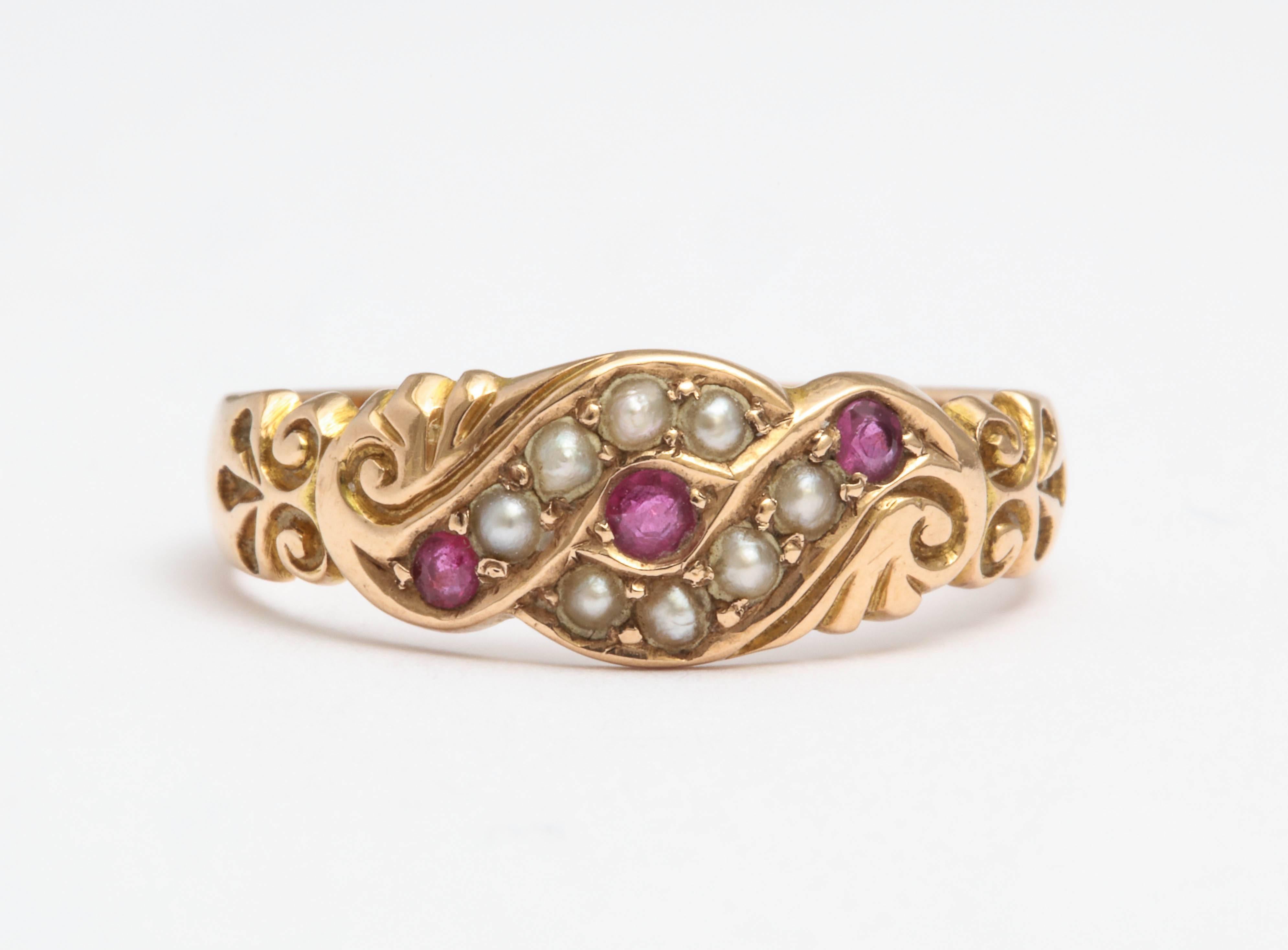 A tapered 15k rose gold ring, the top set with a three small rubies and eight seed pearls, in a beautiful scrolling mount. 

size 7 1/4.   Width of band: 6.5 mm top; 3.2 mm bottom 

Birmingham, date letter k for 2010, 15, 625. 

