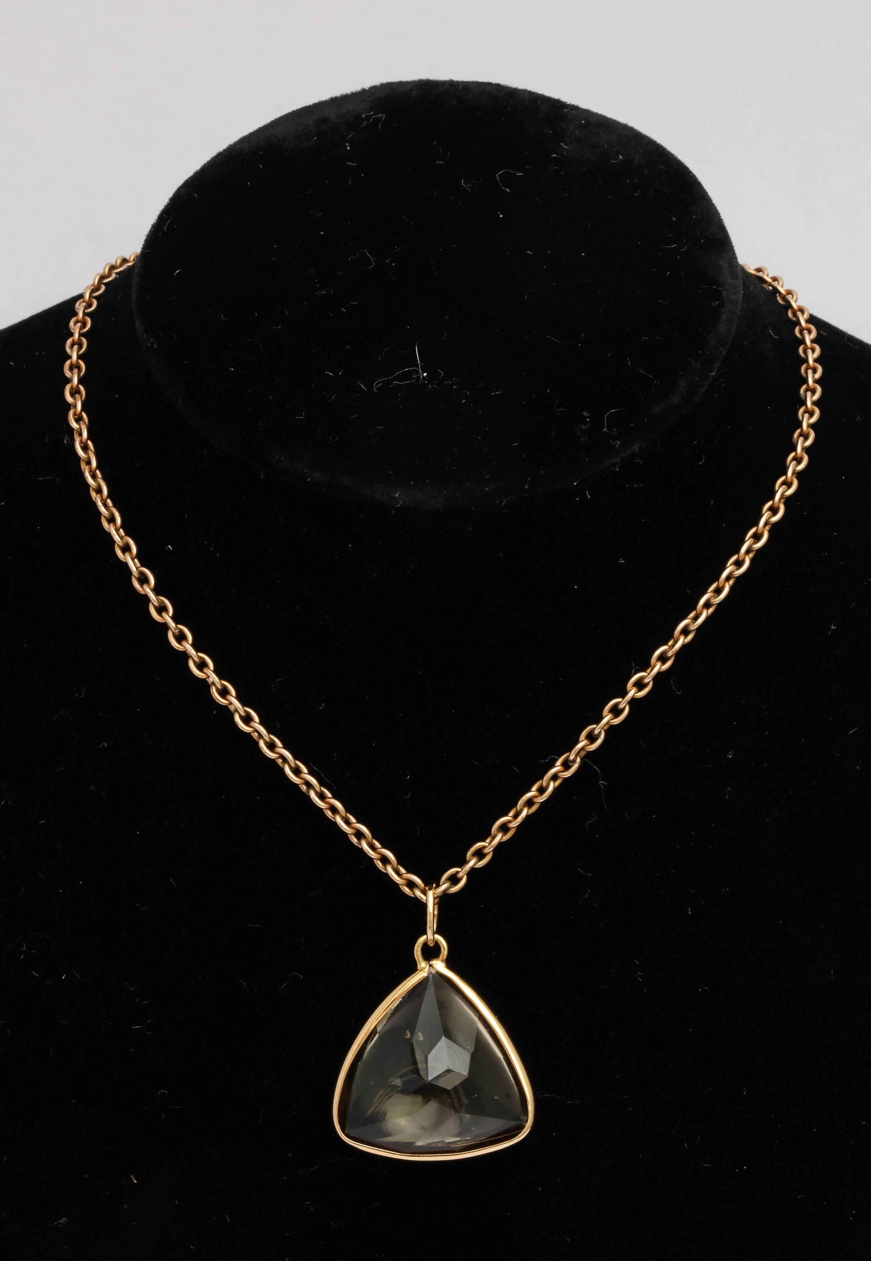 A buff-topped triangular-cut smokey quartz with a faceted reverse, bezel set in yellow gold with gold suspension ring.  Chain not included. 

20th century. 

Pendant measures ¾ in. (1.9 cm.) from one corner to the next.  Quartz measures 8.7 mm deep. 